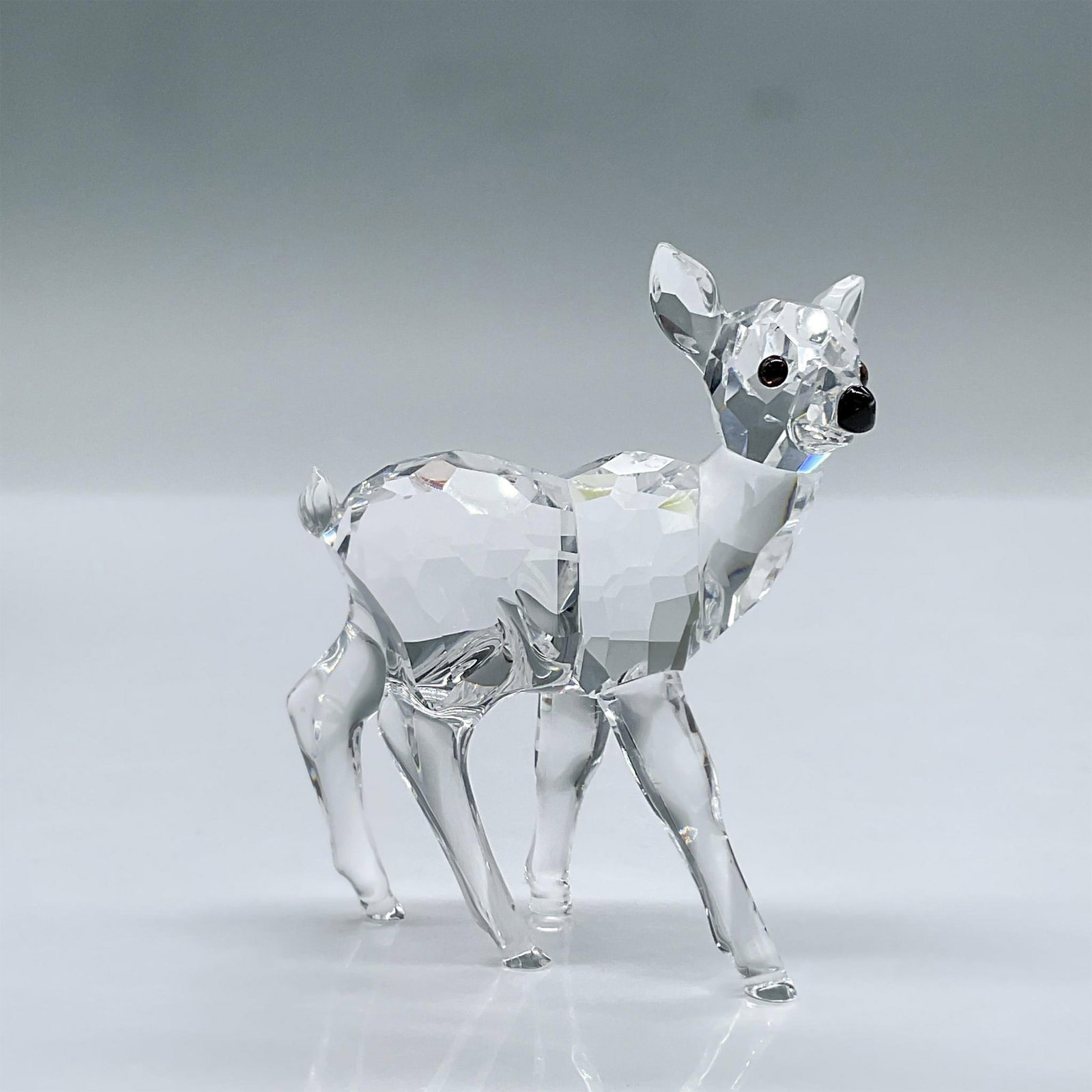 Swarovski Crystal Figurine, Fawn: This adorable fawn has a clear facetted body, smooth moulded legs, and a black nose. This item has its original box measuring 4.75"L x 4.75"W x 4"H. Swarovski acid mark. 235045. Issued: 1999 - 2006 Di