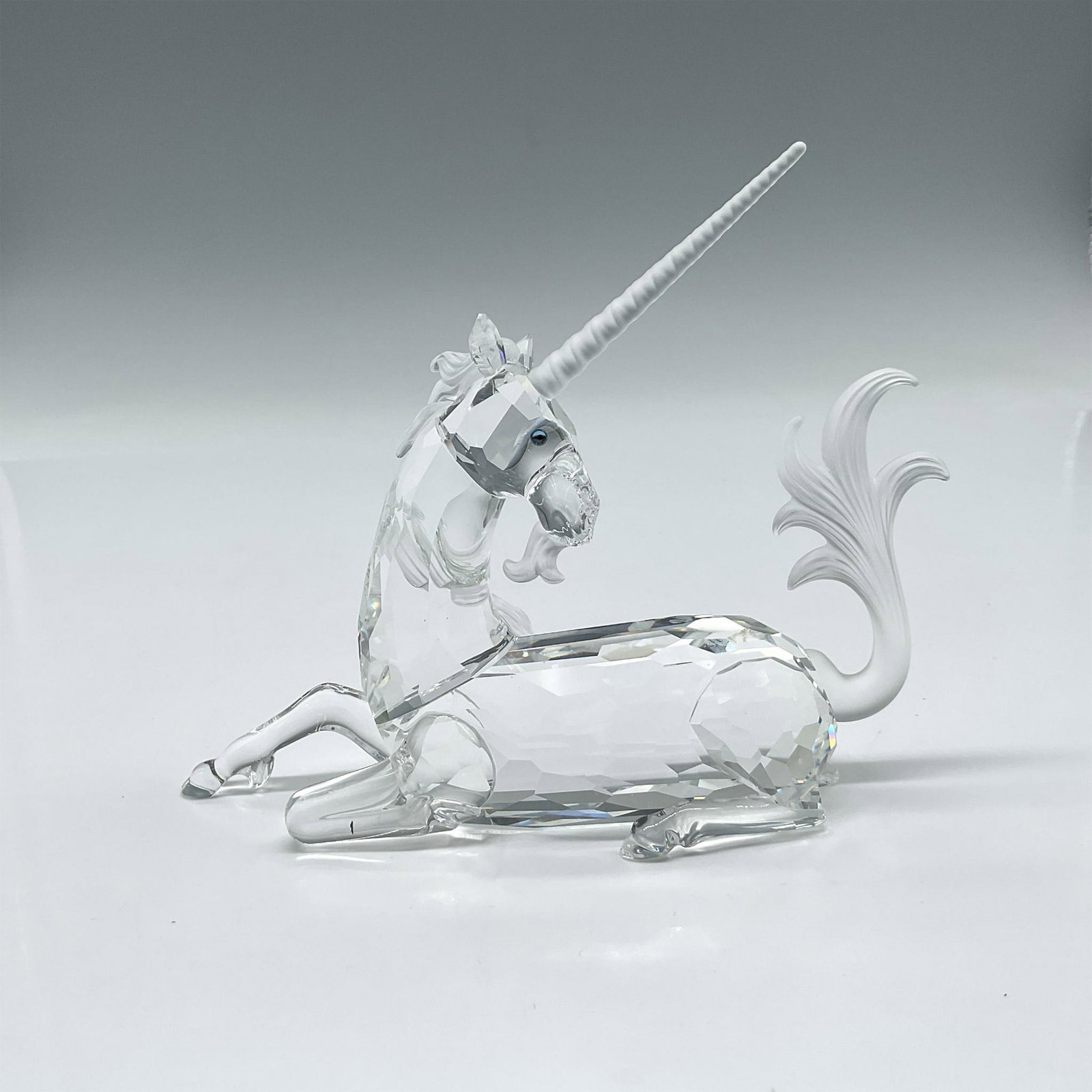 Swarovski Crystal SCS Figurine, Annual Edition The Unicorn: Figure is 1st of the Fabulous Creatures trilogy. Created of faceted clear body, frosted mane, tail, and horn elegantly posed lying down. Swarovski backstamp. 191727. This item has its original box: 10