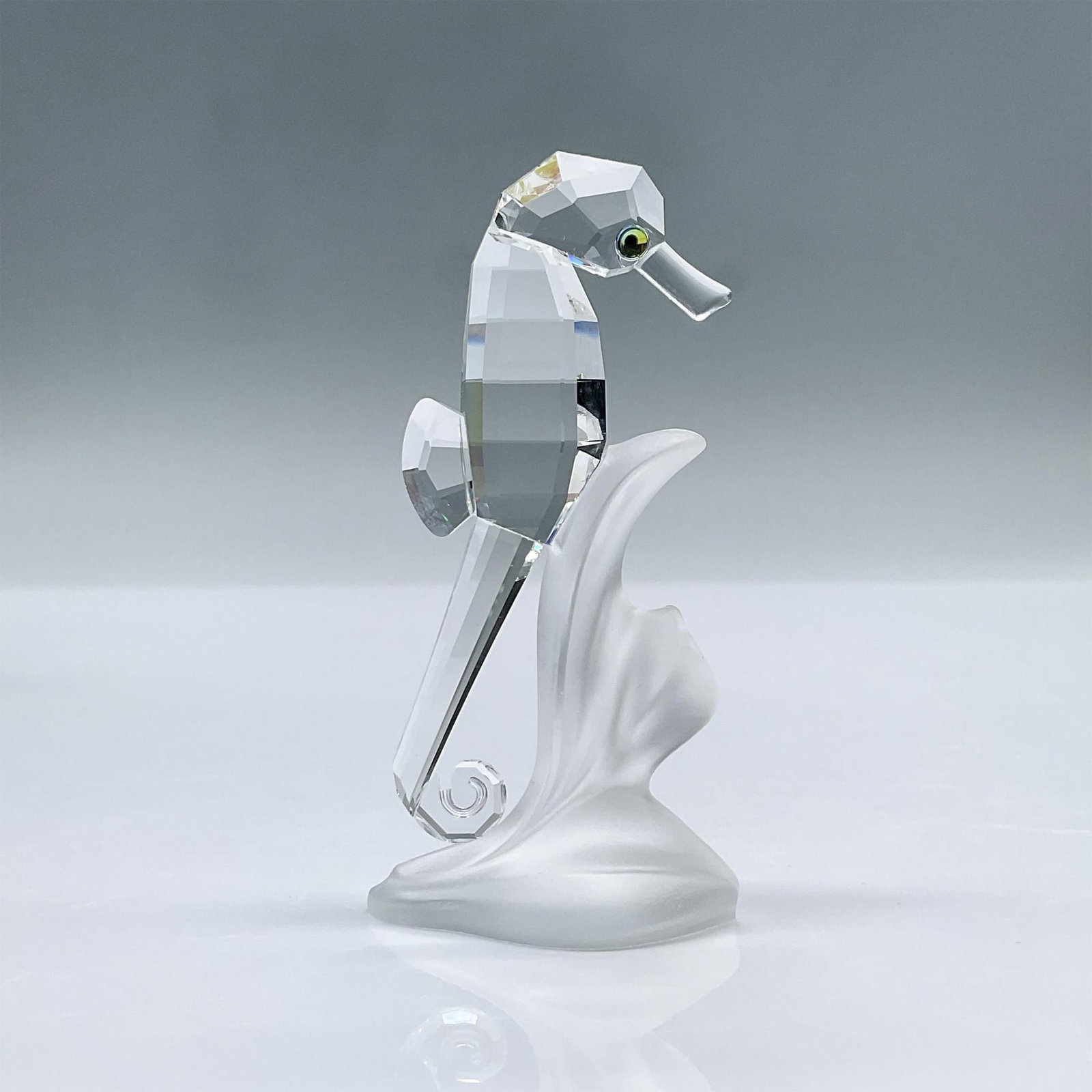 Swarovski Crystal Figurine, Seahorse: This adorable seahorse is made from clear crystal. It's attached to a piece of frosted crystal. This item has its original box measuring 3.25"L x 3.25"W x 6"H. Swarovski acid mark. 168683. Artist: Mic