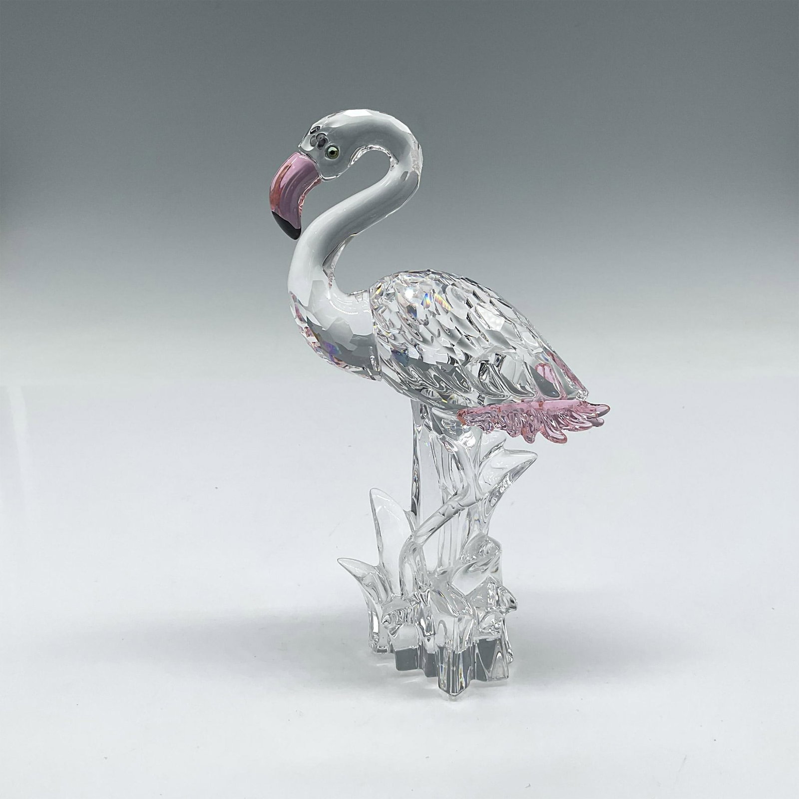 Swarovski Crystal Figurine, Flamingo: Part of the Feathered Beauties collection. Figure is made of faceted clear crystal with smooth crystal neck, head, legs and water. Rosaline crystal accents on beak and tail feathers. Swarovski backsta
