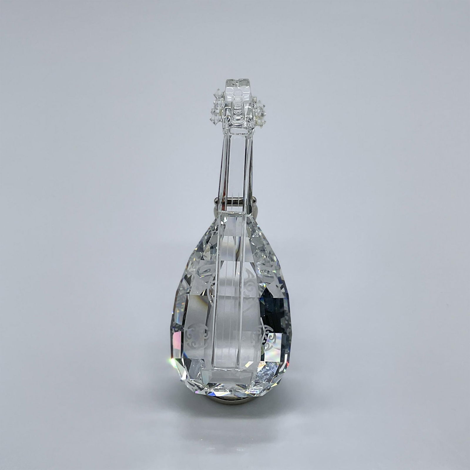 Swarovski Crystal Figurine, Lute: This musical figure is made from clear crystal, and it comes with a rhodium stand. This item has its original box measuring 3.25"L x 3.25"W x 6"H. Swarovski acid mark. 169246. Artist: Martin Zendron I