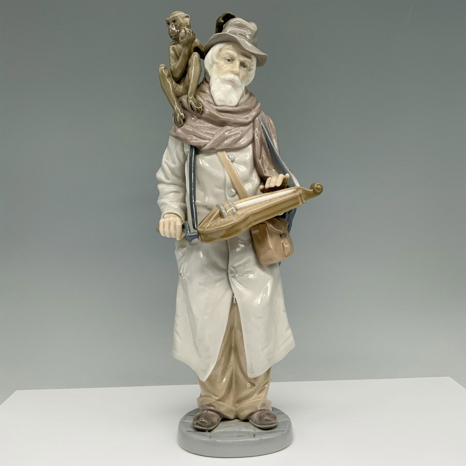 Organ Grinder 01005046 - Lladro Porcelain Figurine: Glossy finish. Figure of an elderly man with a monkey on his shoulder, holding a musical instrument. Lladro backstamp. Artist: Salvador Furio Issued: 1980-1981 Dimensions: 4.25"L x 4.5"W x 3.5"H Manuf