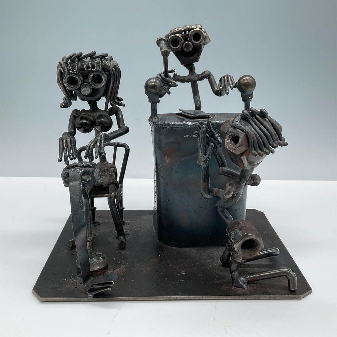 Vintage Metal Sculpture, Courtroom, Signed: Made from various metal parts, such as bolts, screws, and wires, creatively assembled to form three human-like figures in a courtroom scene. Signed on base by artist: Callium. Dated '74. Issued: c. 19