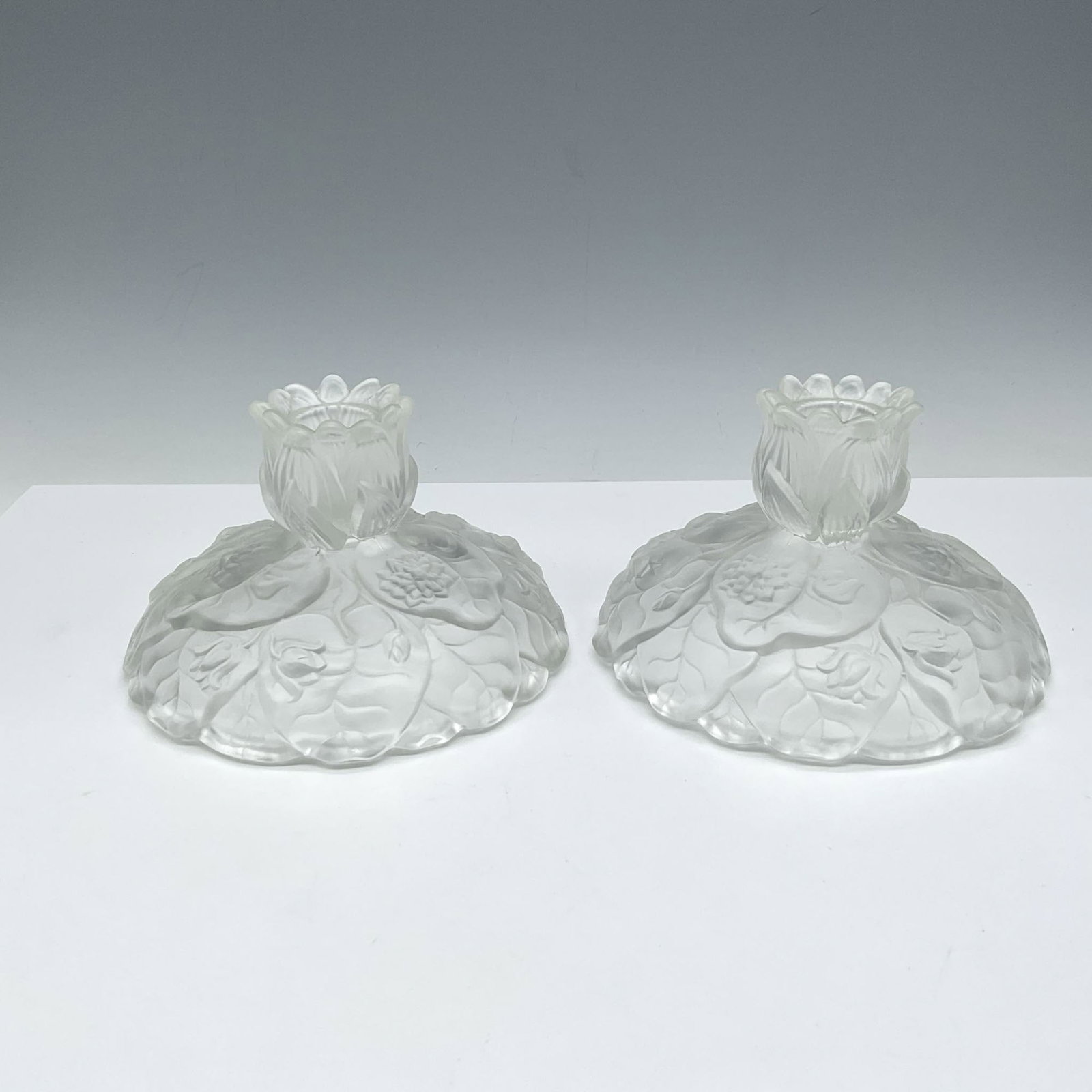 Pair of Fenton Satin Glass Water Lily Candleholders: Elegant molded floral and leaf design on full round base with short holders. Issued: 20th century Dimensions: 3.5"H x 5.25" dia. Manufacturer: Fenton Country of Origin: United States