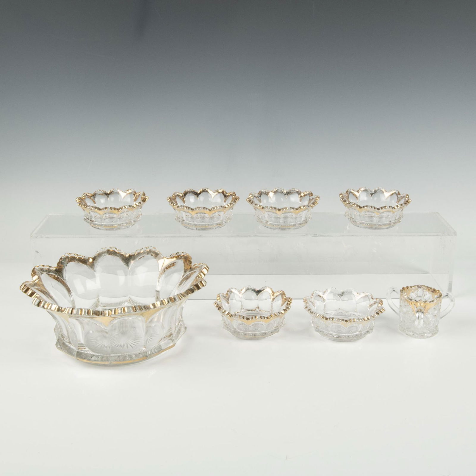 8 pc Heisey Peerless Clear Glass w/ Gold Trim Serveware: Lovely Heisey Peerless clear glass serveware with a facet curved design enhanced with gold trim designs. Includes 1 large bowl, 6 small bowls, and 1 trinity tyg cup. Markings: H inside bowls. Largest
