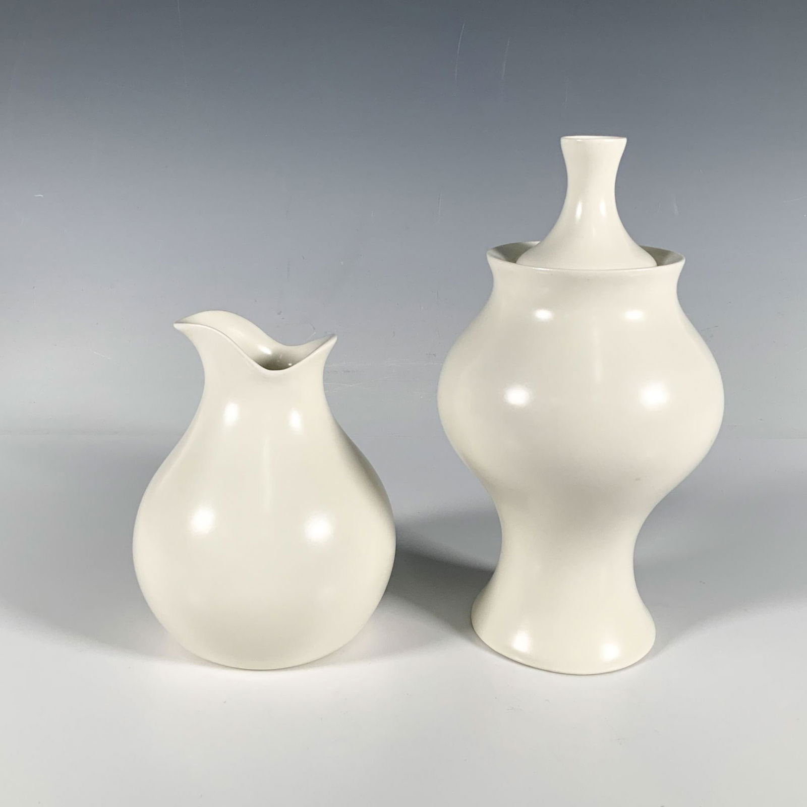 2pc Eva Zeisel For Klein Reid Porcelain Lidded Vase & Carafe: This minimalist set of modern home decor includes a lidded vase and carafe, designed by Hungarian designer and ceramist Evan Zeisel, finished in a soft white satin glaze. Klein Reid Eva Zeisel backsta
