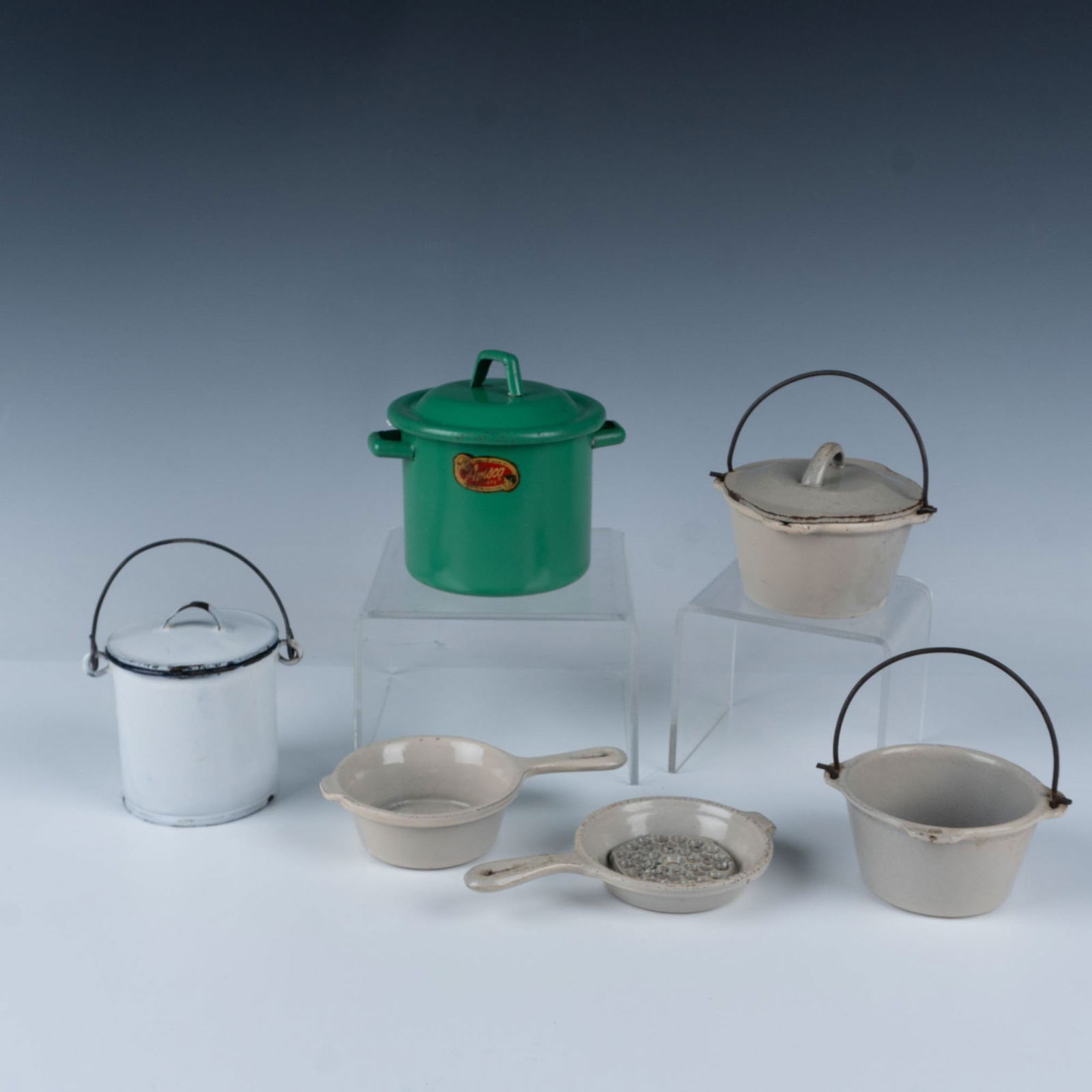7pc Mini Kitchenware, Lidded Pot & Amsco Toys Bottle Warmer: Includes a 5 piece beige cast iron enamel set of two skillets, a pot with a handle, a lidded pot with a handle and an oven trivet. Also included is a white enamel lidded pot and a green Amsco Toys kid