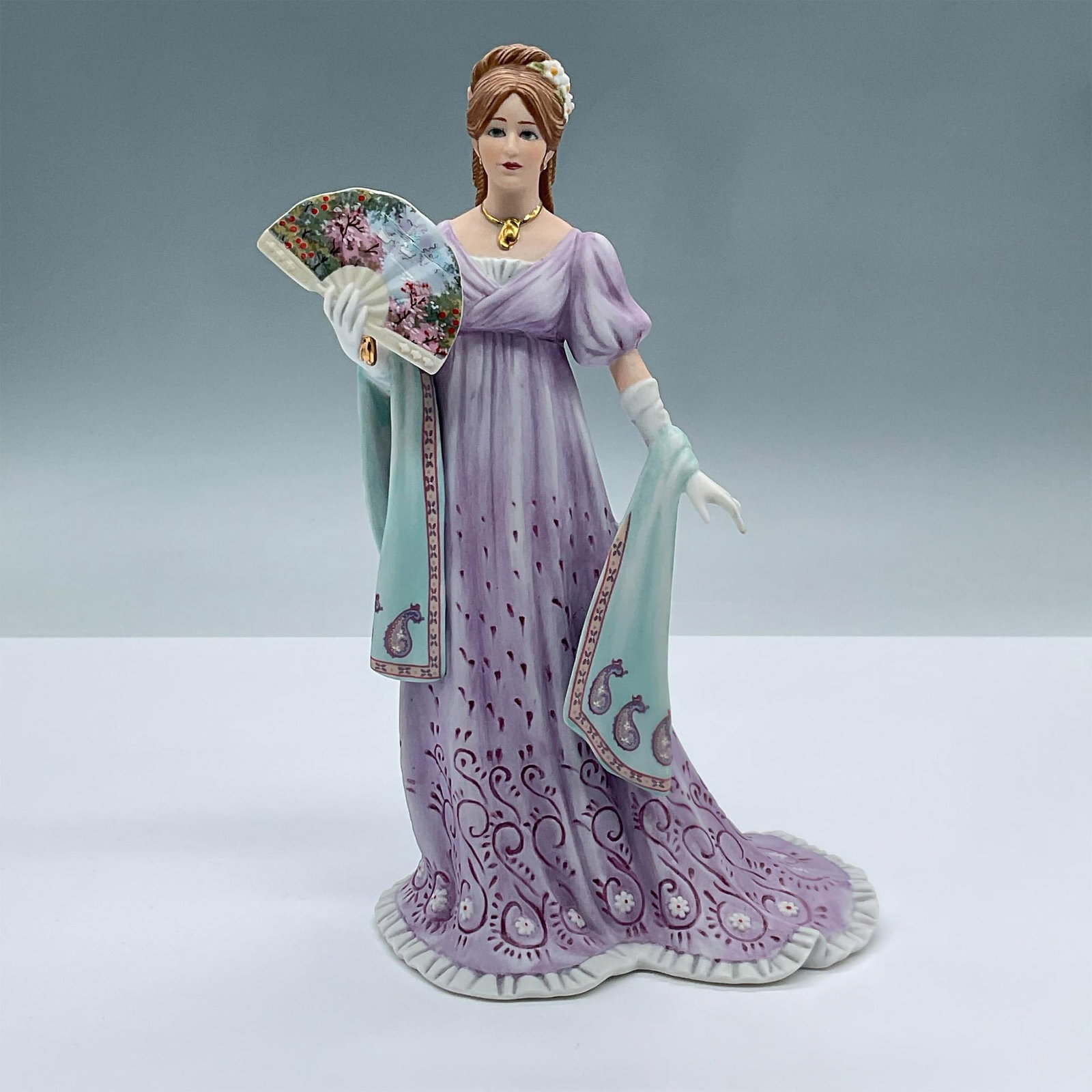 Lenox Fine Porcelain Figurine, Gala At the White House: This fine porcelain figure features a lovely lady dressed in purple with a gilded gold necklace, holding a fan. Lenox backstamp. Issued: 20th century Dimensions: 5"L x 4"W x 8.5H Manufacturer: Lenox C