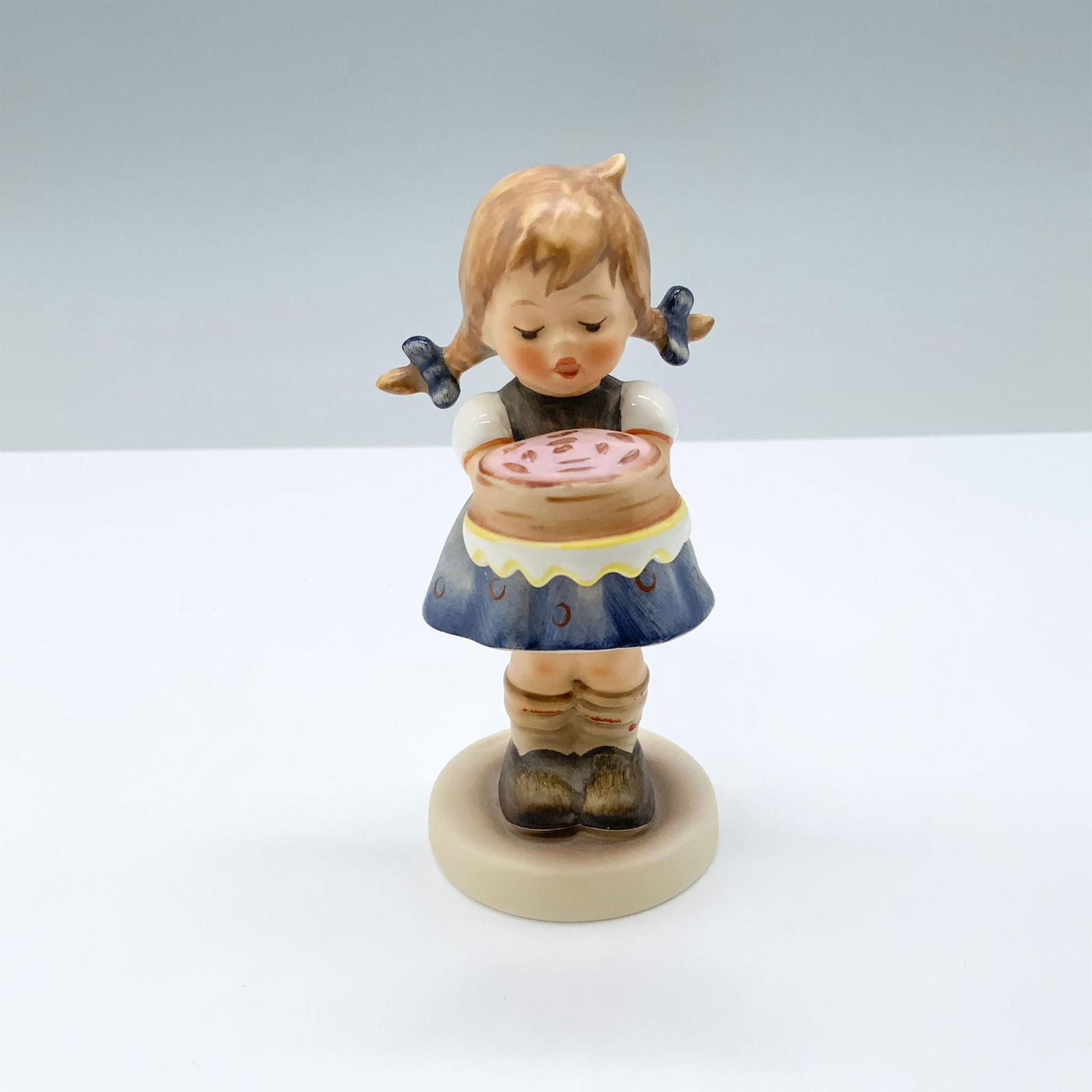 Goebel Hummel Porcelain Figurine, Sweet As Can Be: Figure of a girl with pig tails holding a cake. M.I. Hummel impressed. Goebel backstamp. 143/Hum 541. This item has its original box. Box measures: 5.75"L x 3.5"W x 3.5"H. Dimensions: 2.5"L x 2"W x 4.