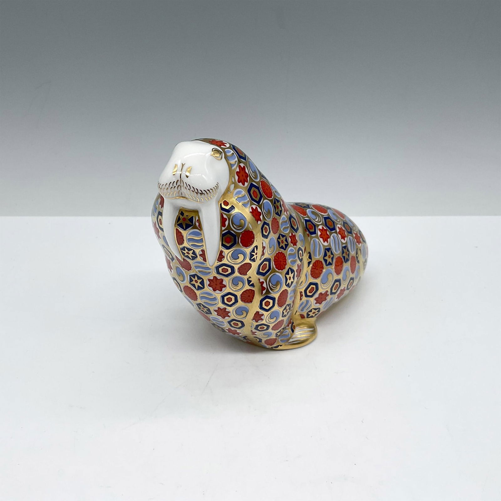 Royal Crown Derby Bone China Paperweight, Sea Lion: The majestic hand painted, colorful figure sits with tusk prominently displayed. Colored in sienna, blue, and gilt incorporated throughout design including his facial features. Royal Crown Derby backs