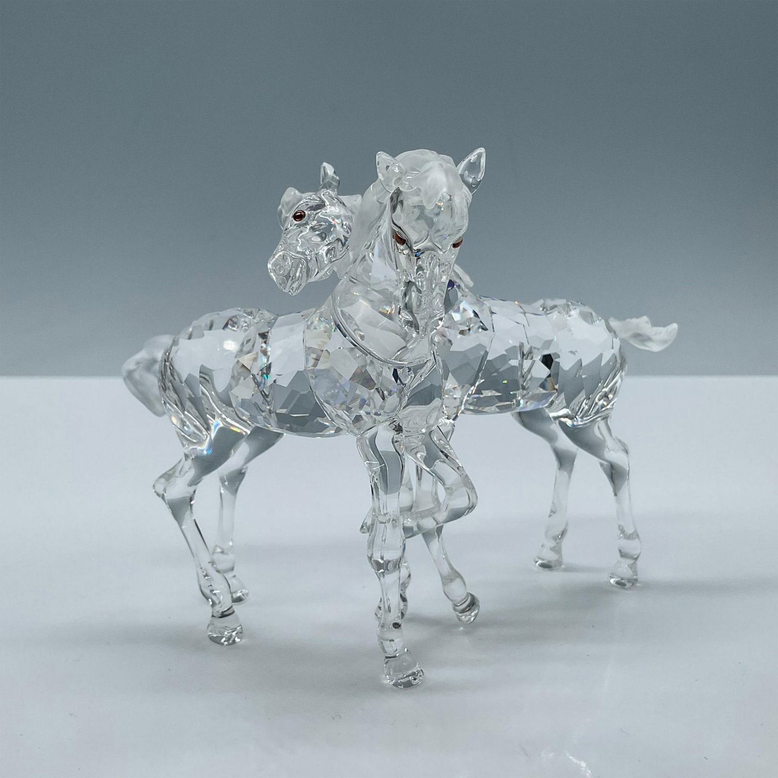 Swarovski Crystal Figurine, Clear Foals Playing: Part of the Peaceful Countryside theme group. Young horses at play are created with clear faceted bodies with satin crystal manes and tails. Eyes are smoked topaz crystal. Swarovski backstamp. Include