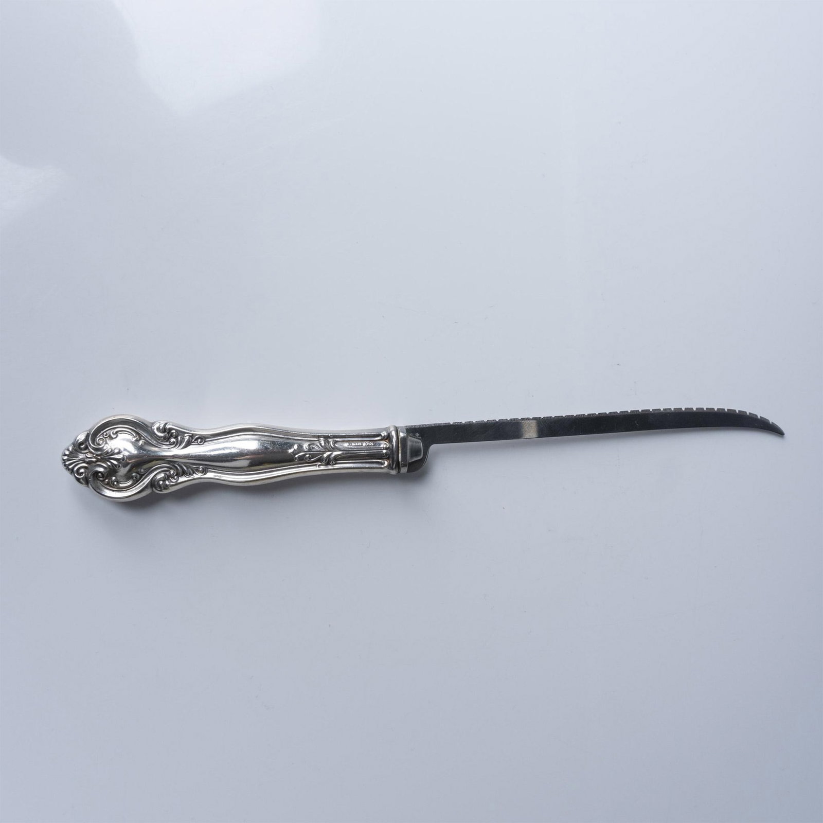 Frank Whiting Sterling Silver and Steel Carving Knife: An elegant sterling silver and steel carving knife crafted by Frank Whiting & Company, featuring an ornate handle with intricate scrollwork and acanthus leaf motifs. The handle is marked "Sterling" wi