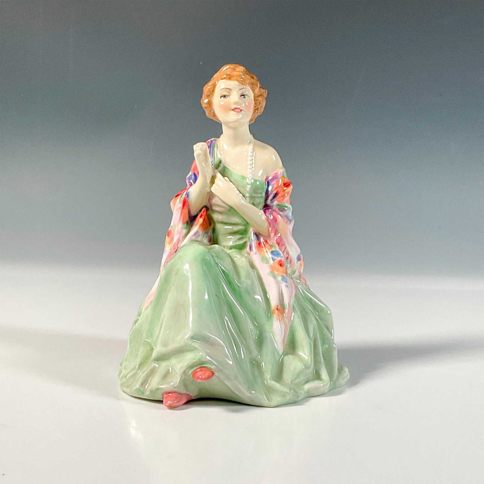 Royal Doulton Figurine, Aileen HN1645: Glazed bone china figure of lady in a green dress, colorful shawl, holding part of her pearl necklace. Royal Doulton backstamp. Artist: Leslie Harradine Issued: 1934-1938 Dimensions: 4.25"L x 4.75"W x
