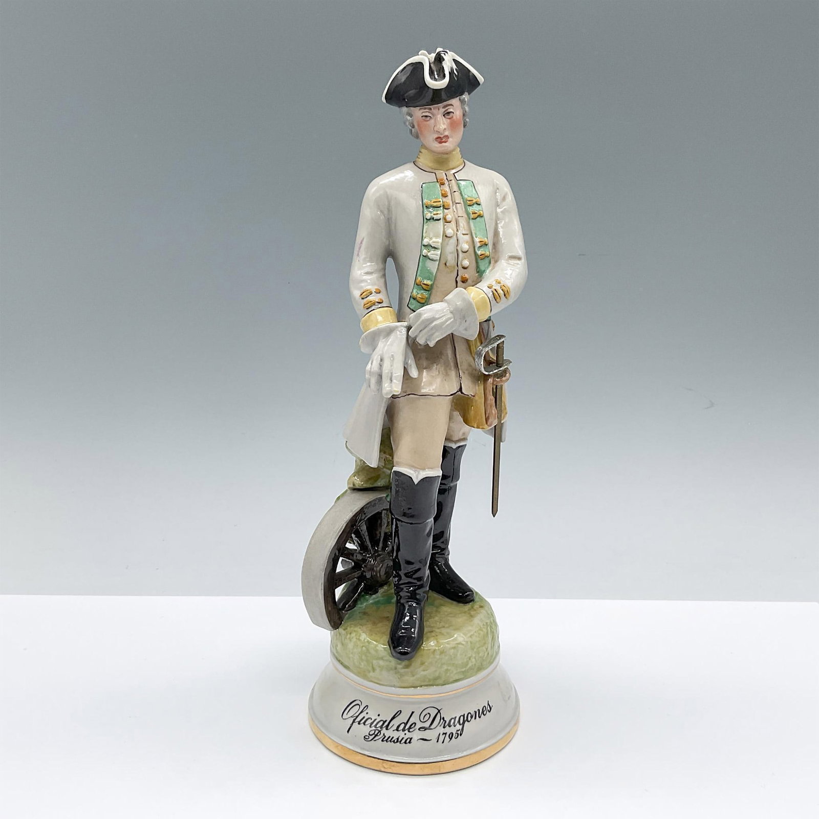 Sureda Porcelain Figurine, Oficial de Dragones Prusia-1795: Hand decorated figure of a soldier in gray and green dress uniform. He is shown adjusting his glove. Sureda blue backstamp. Issued: 20th century Dimensions: 4.25"L x 4"W x 10.75"H Manufacturer: Sureda