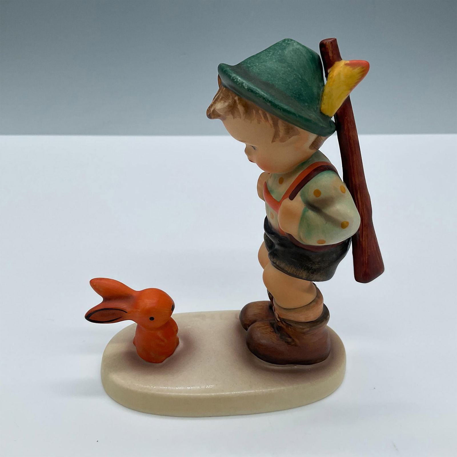 Goebel Hummel Figurine, Sensitive Hunter: Beautifully hand painted porcelain of an adorable young boy carrying a rifle timidly hunting who comes face to face with a rabbit. Goebel Hummel backstamp Artist: Arthur Moller Issued: 1984 Dimensions