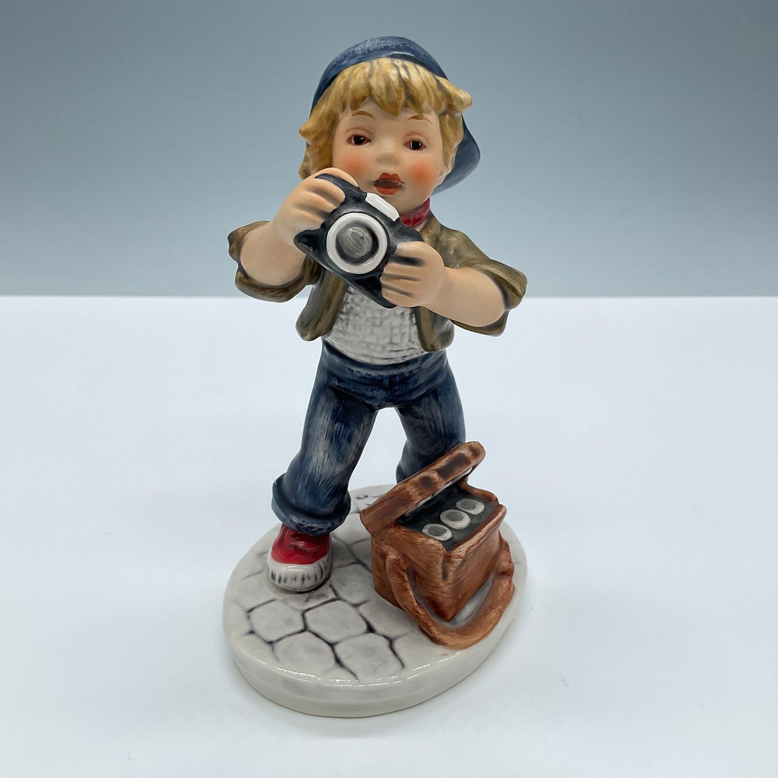 Goebel Hummel Figurine, Today's Children Little Photographer: Beautiful matte finish. Features a little boy taking photographs. Signed Frobek. Goebel Hummel Today's Children backstamp. Issued: 20th century Dimensions: 4''L x 3''W x 6''H Manufacturer: Goebel Humm