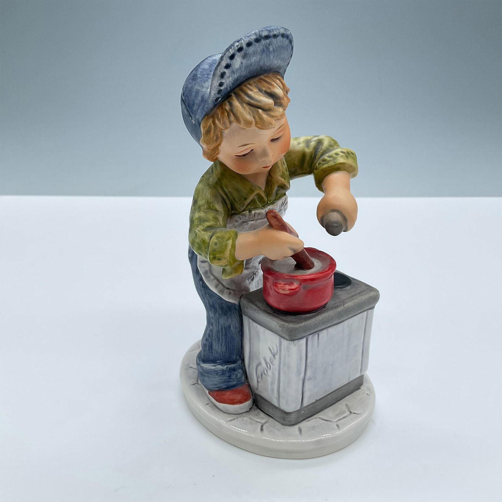 Goebel Hummel Figurine, Today's Children Weekend Chef: Matte finish. Features a little boy cooking. Signed Frobek. Goebel Hummel Today's Children backstamp. Issued: 20th century Dimensions: 3.5''L x 3''W x 6.25''H Manufacturer: Goebel Hummel Country of Or