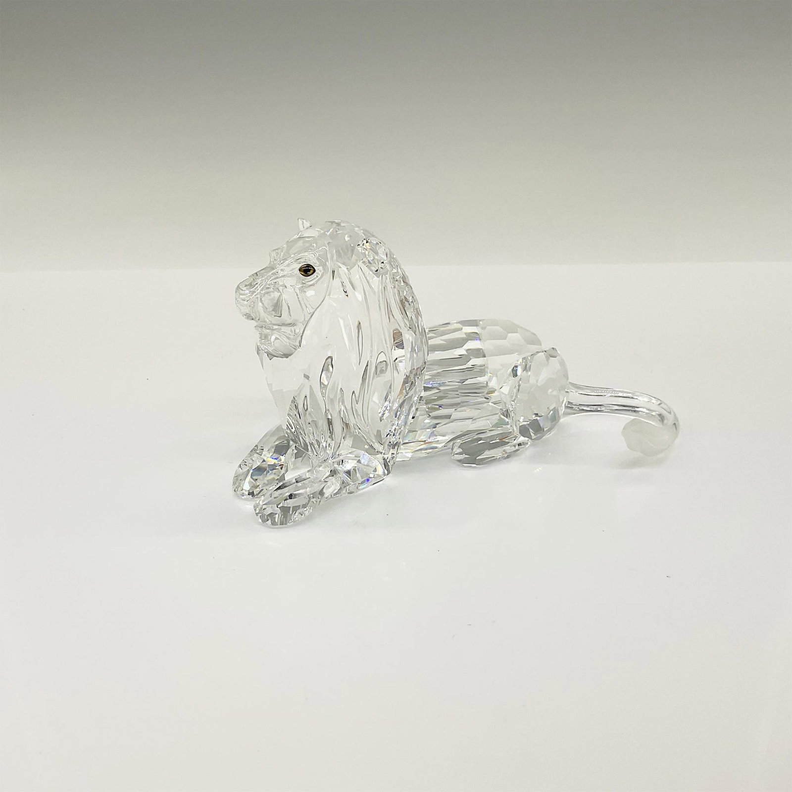 Swarovski SCS Crystal Figurine, The Lion Inspiration Africa: Brilliant clear crystal Annual Edition, Inspiration Africa, The Lion in a sitting position. This item has its original box which measures: 7.5"L x 6.5"W x 7.5"H. Signed Adi Stocker. Swarovski backstam