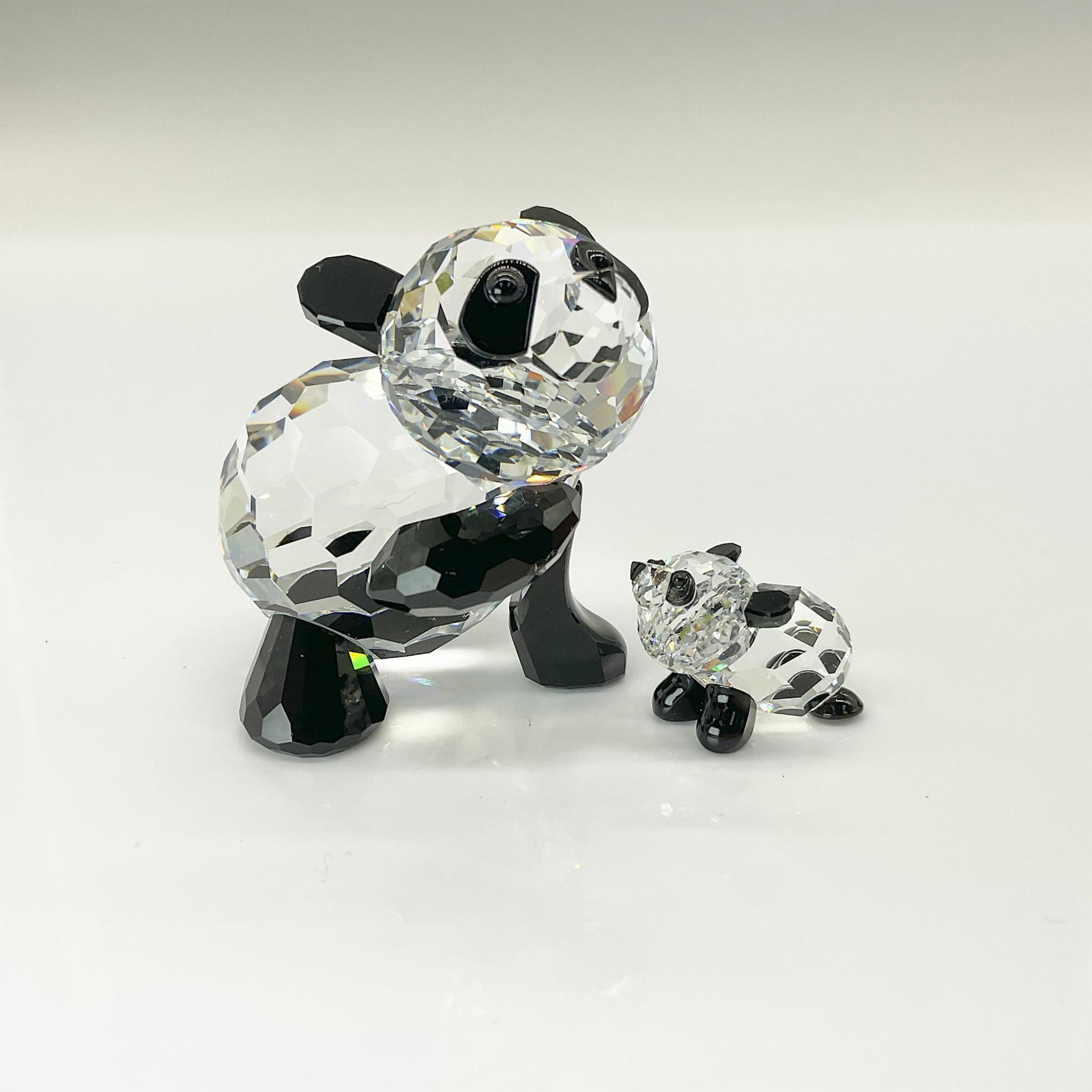 2pc Swarovski Crystal Figurine, Panda Mother and Mini Panda: This Panda was the first Swarovski animal to feature extensive use of black crystal, previously reserved primarily for eyes and noses. A mirror coating prevents the black crystal from being seen throu