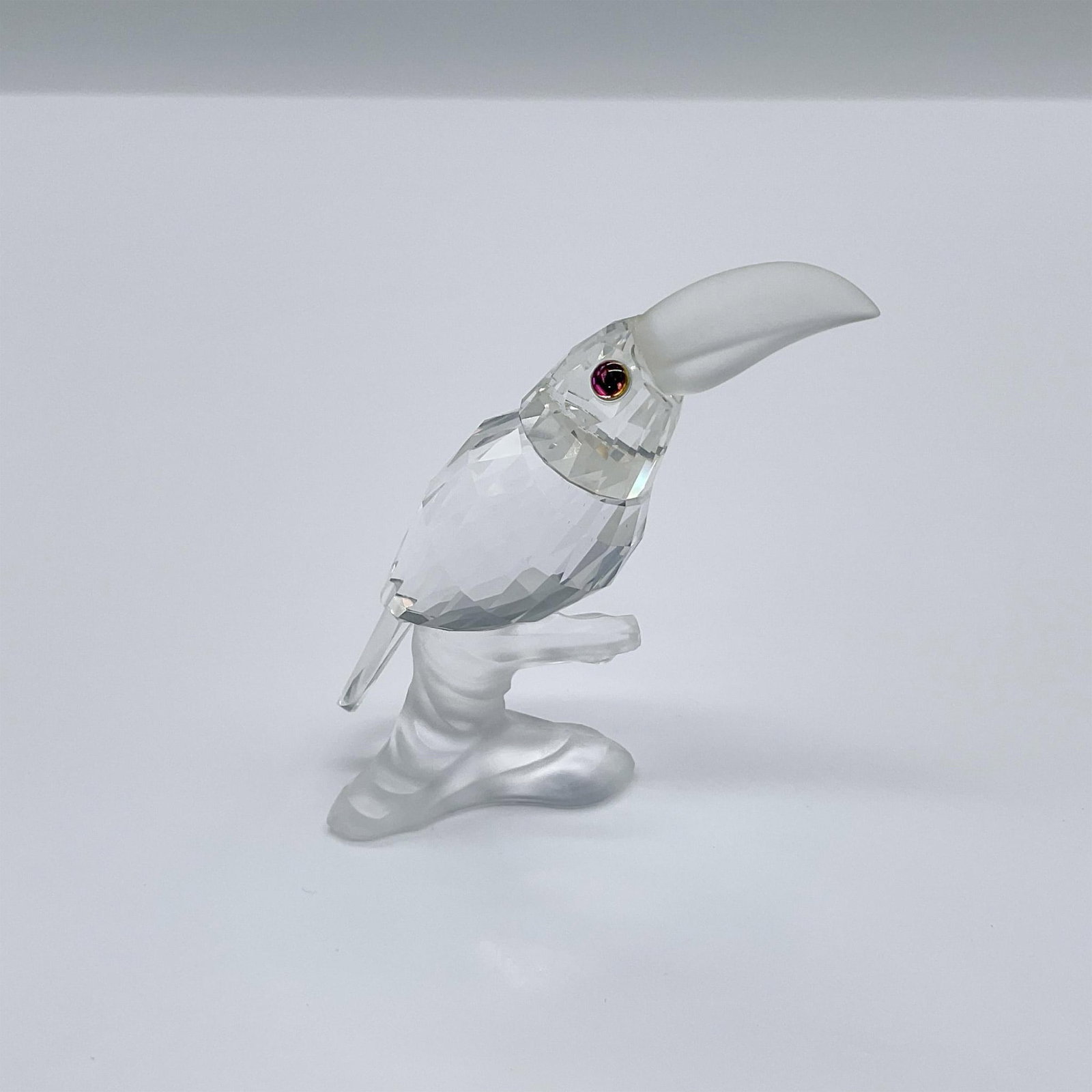 Swarovski Crystal Figurine, Toucan On Branch: From the Up In The Trees theme. A clear crystal tropical bird with a frosted beak perched on a frosted base. Swarovski swan mark. 119441. This item has its original box: 3.25"W x 5"H. Artist: Michael 