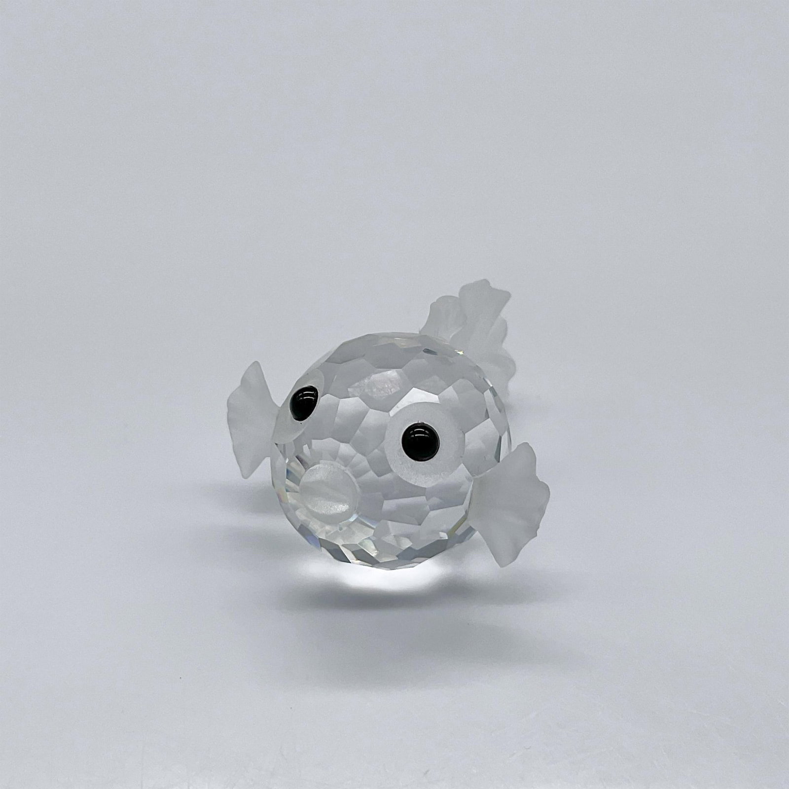 Swarovski Crystal Figurine, Blowfish - Mini: Part of the South Sea theme. A clear facetted crystal with frosted crystal fins, tail, and mouth. Eyes are made from black crystal. Swarovski swan mark. 013960. This item has its original box: 2.5"W x