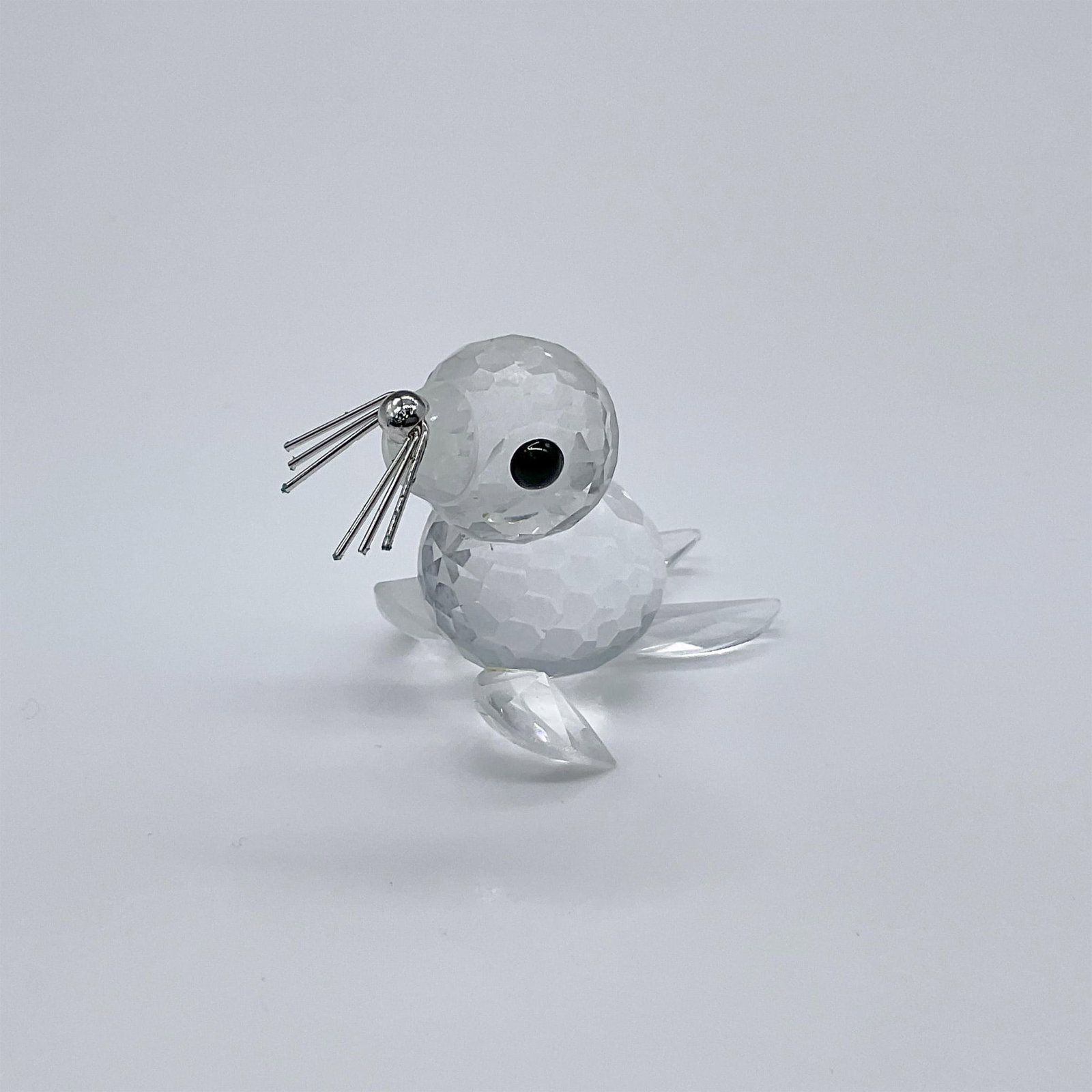 Swarovski Crystal Society Figurine, Seal - Silver Whiskers: Part of the Kingdom Of Ice And Snow collection. A mini clear crystal seal pup with black eyes and silver whiskers. Swarovski Crystal Society mark. 012530. This item has its original box: 3.25"W x 2.5"