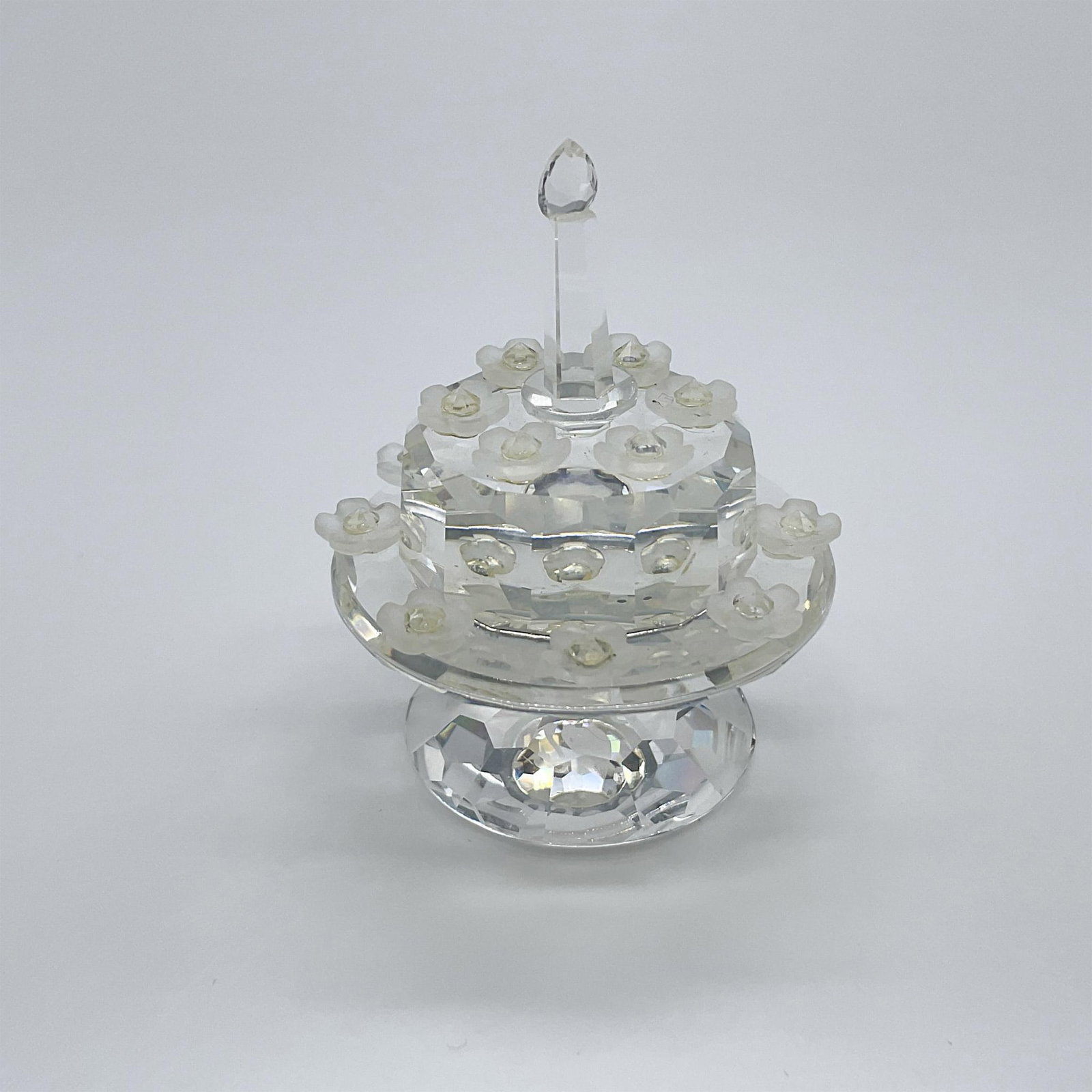 Swarovski Crystal Society Figurine, 1992 Birthday Cake: An exclusive jubilee edition for SCS members. A clear crystal cake on a stand with little frosted flowers around a single candle. Swarovski SCS swan mark. 169678. This item has its original box: 3.25"
