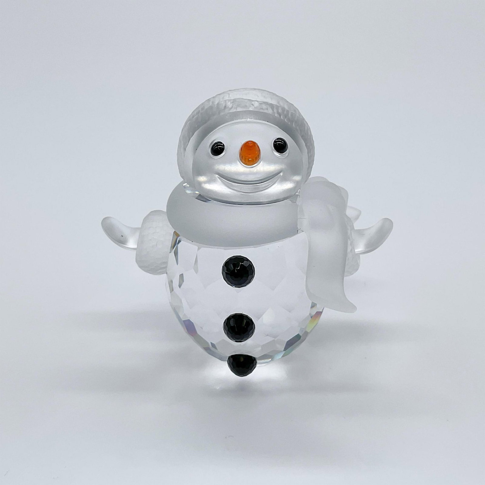Swarovski Crystal Figurine, Snowman: Part of the Cheerful Times, and When We Were Young collection. A clear crystal snowman with frosted face, hat, and scarf. Black crystal eyes and buttons, and a orange crystal carrot nose. Swarovski sw