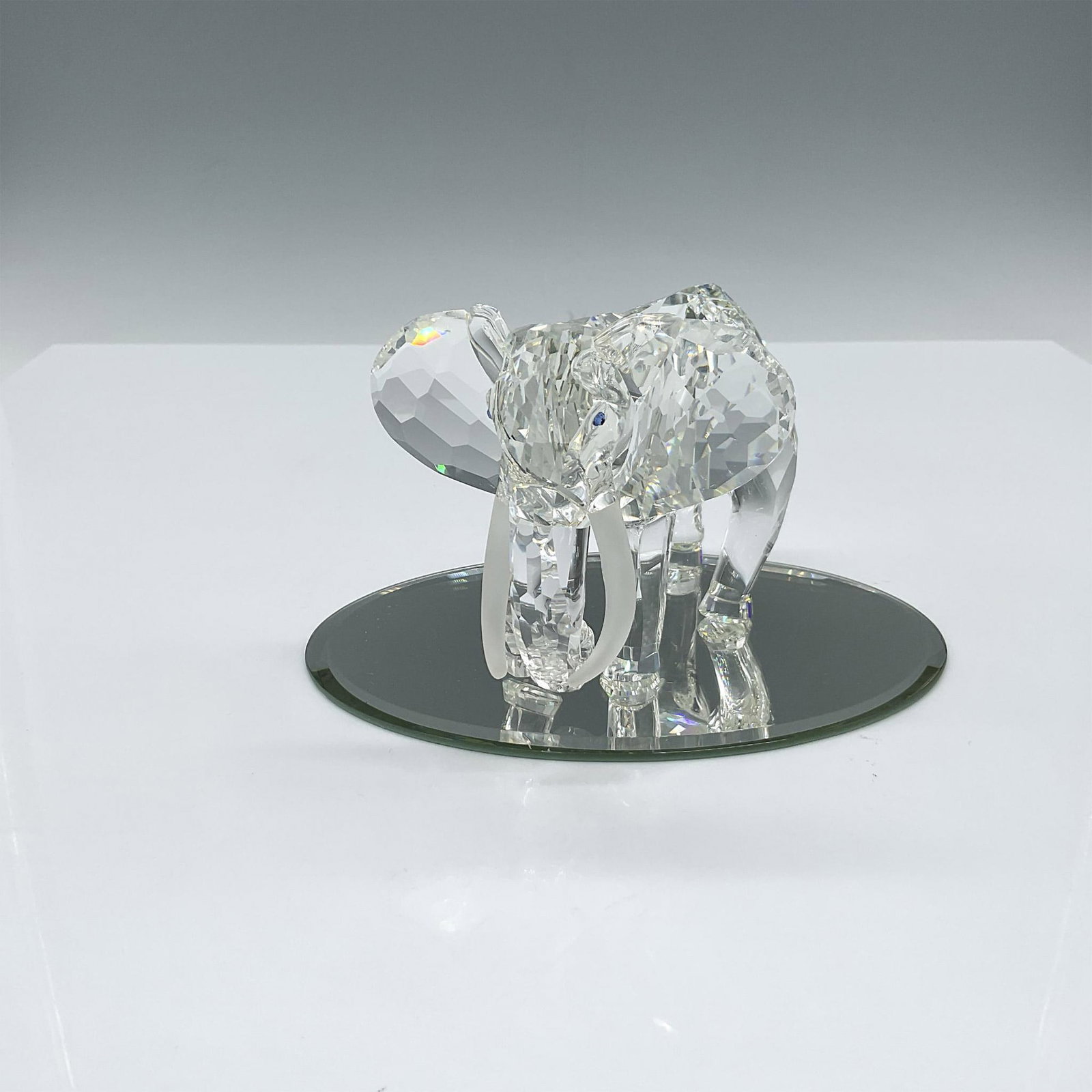 Swarovski SCS Figurine, Inspiration Africa Elephant: Spectacular clear crystal elephant mid-stride with trunk curled under, and satin tusks. Swarovski backstamp. This item has its original box: 7.5"L x 7.5"W x 7"H. This item has a oval mirrored base inc