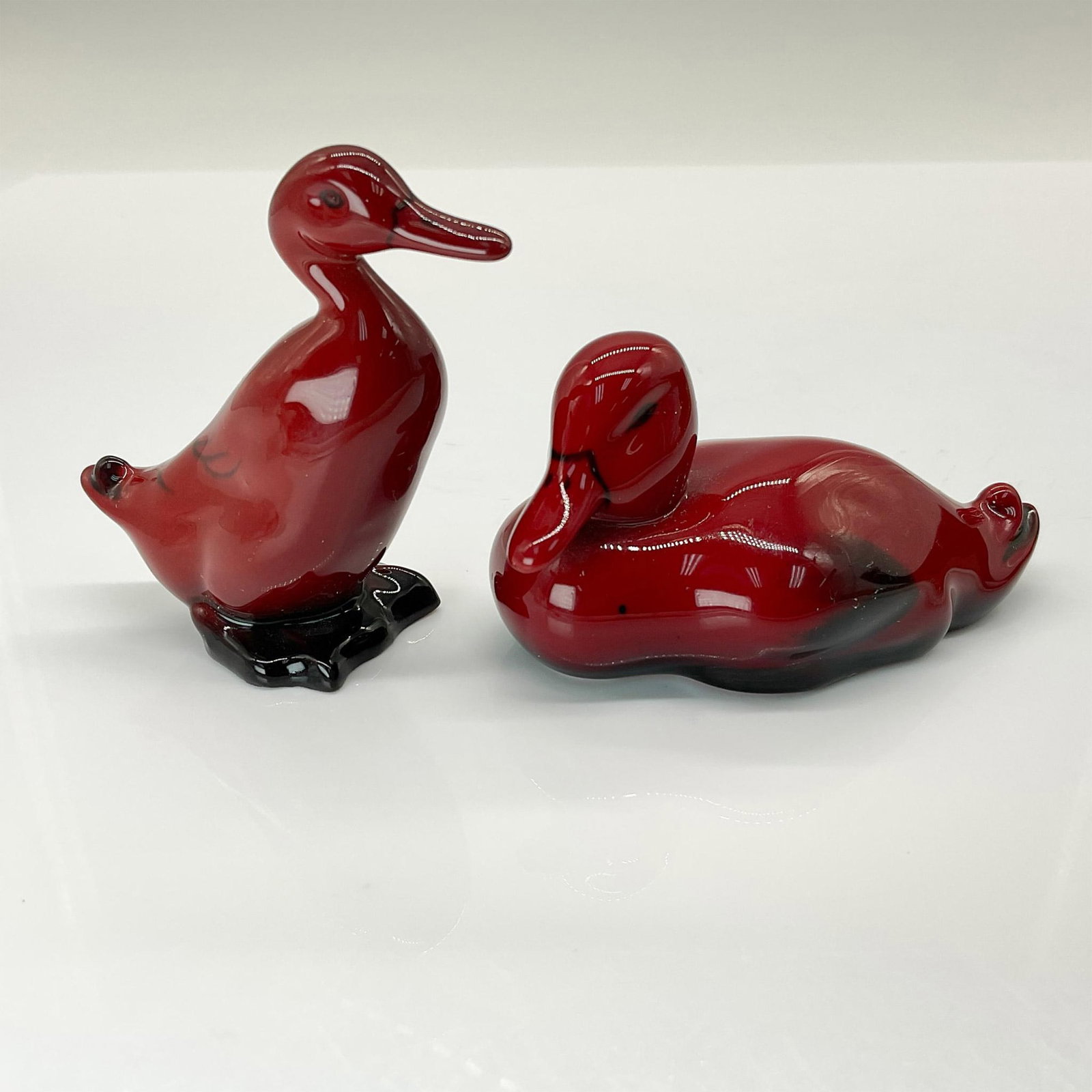 2pc Royal Doulton Flambe Duck Figurines: Standing Duck (HN806) and Resting Duck (HN148B) figurines, featuring a rich red glaze with black accents. Both include authentic Royal Doulton backstamps. Dimensions: Standing Duck: 2.5"L x 1.25"W x 2