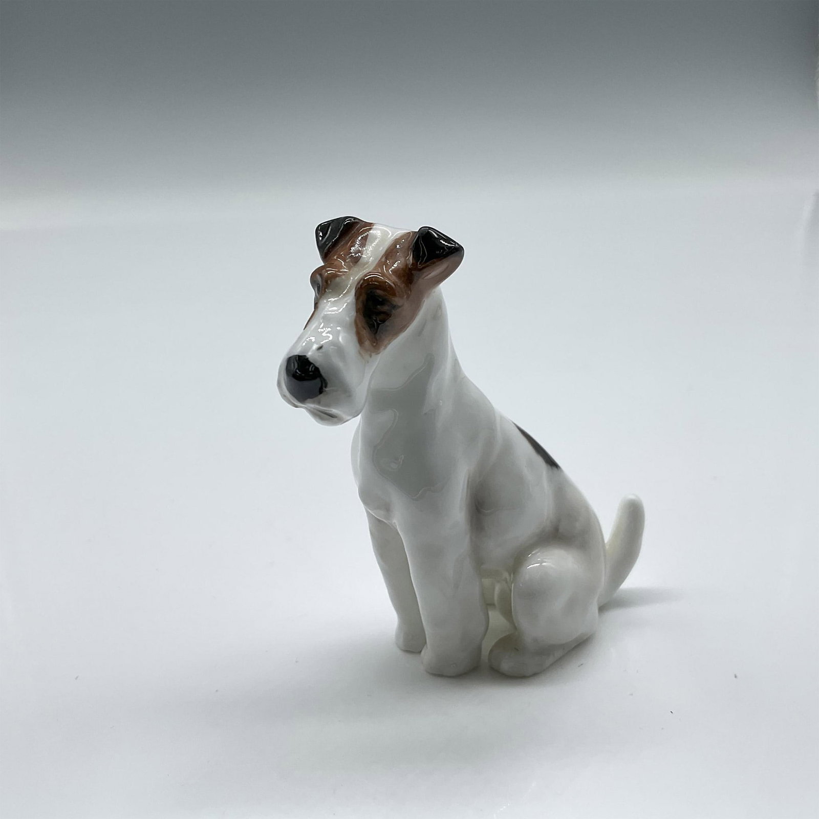 Fox Terrier K8 - Royal Doulton Animal Figure: Seated with head tilted colored in white with black and brown patches. Royal Doulton backstamp. Issued: 1931 - 1977 Dimensions: 2.5"H Manufacturer: Royal Doulton Country of Origin: England