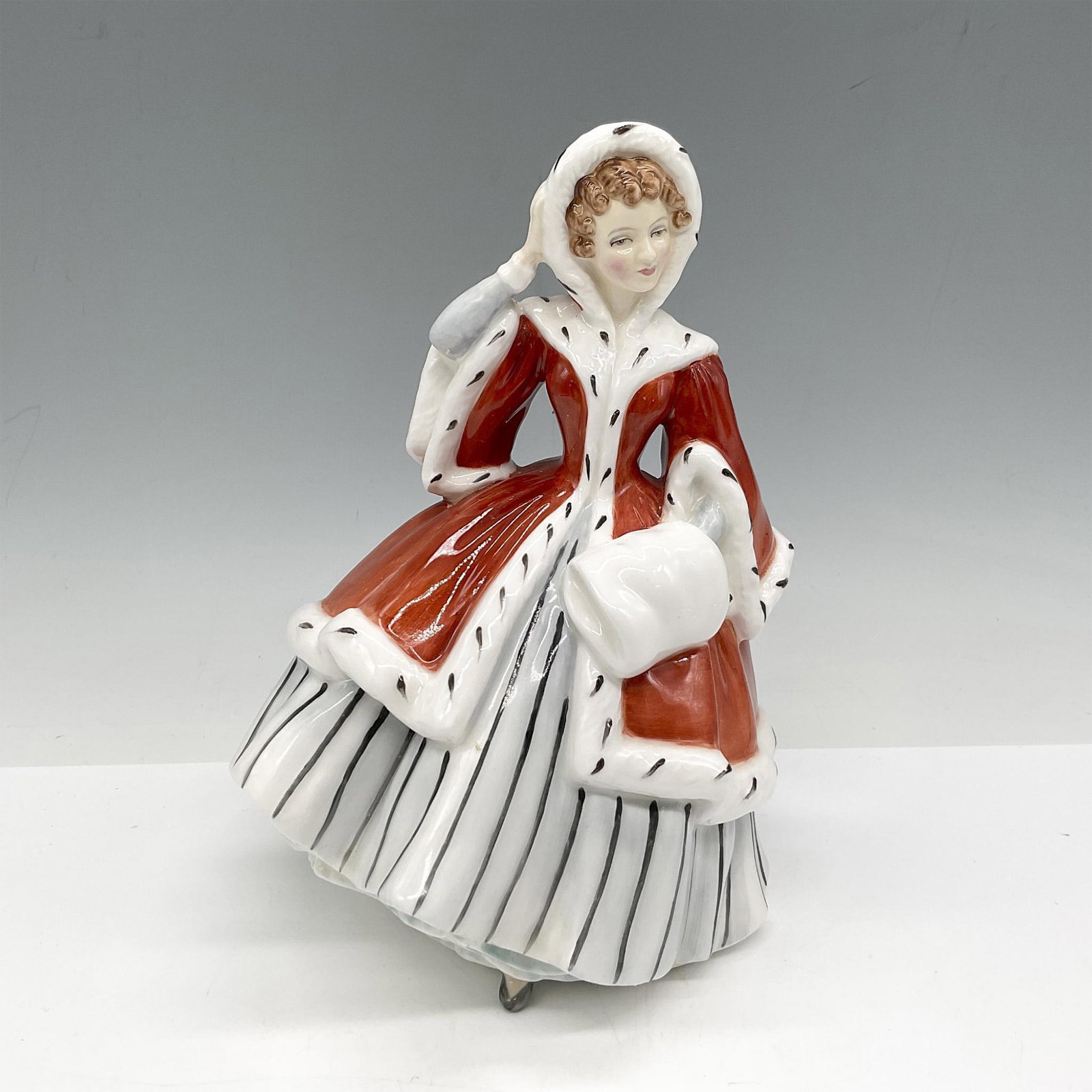 Noelle - HN2179 - Royal Doulton Figurine: Part of the Christmas Holiday series, figure is dressed in red and white coat over a black and white striped dress, carrying a hand muff. Royal Doulton backstamp. Artist: Peggy Davies Issued: 19547 - 