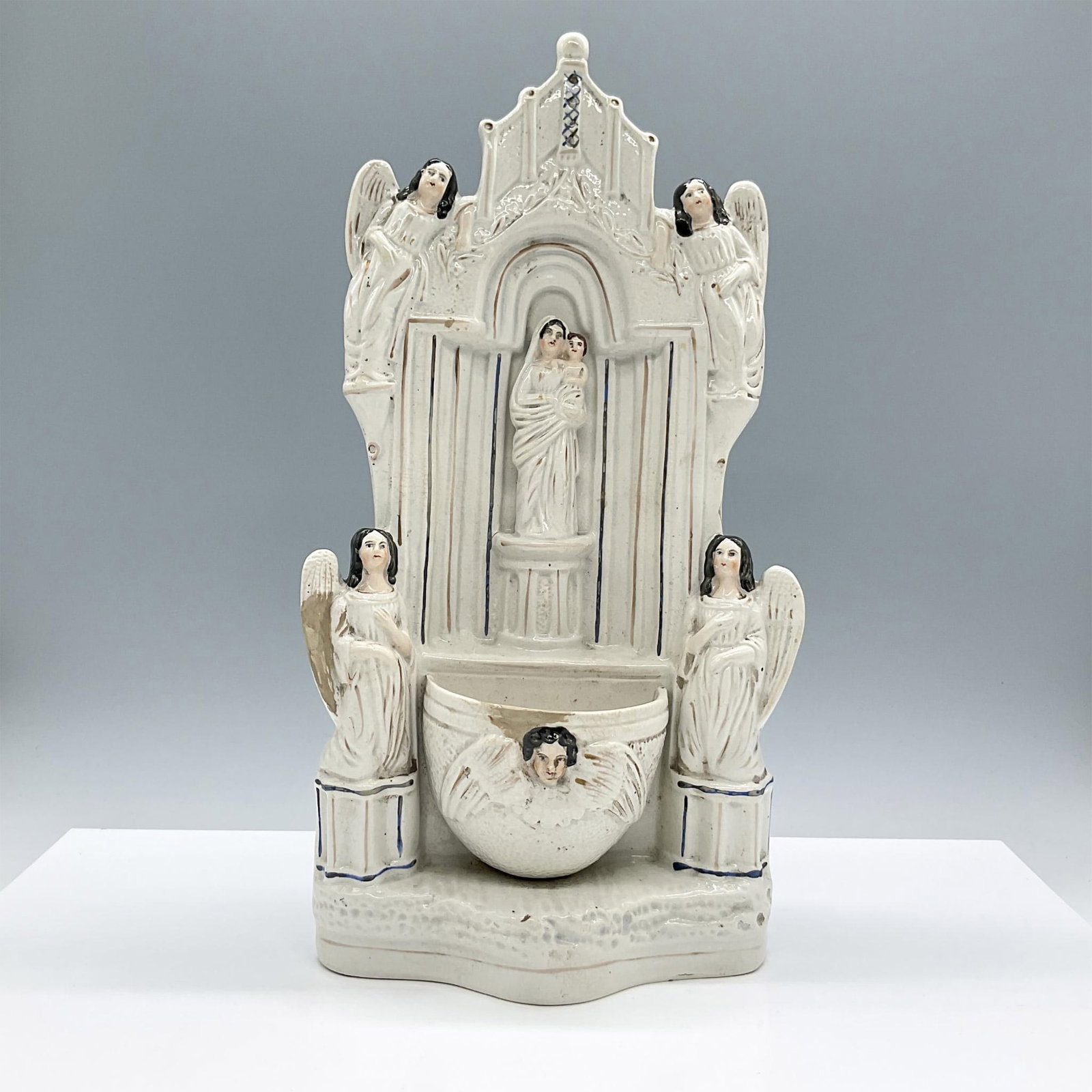 Antique Staffordshire Ceramic Holy Water Font, Virgin Mary: Handcrafted and painted piece. Features the Virgin Mary holding baby Jesus, placed within an arched niche, surrounded by angels. Completed by a small bowl-like basin, typically used to hold holy water