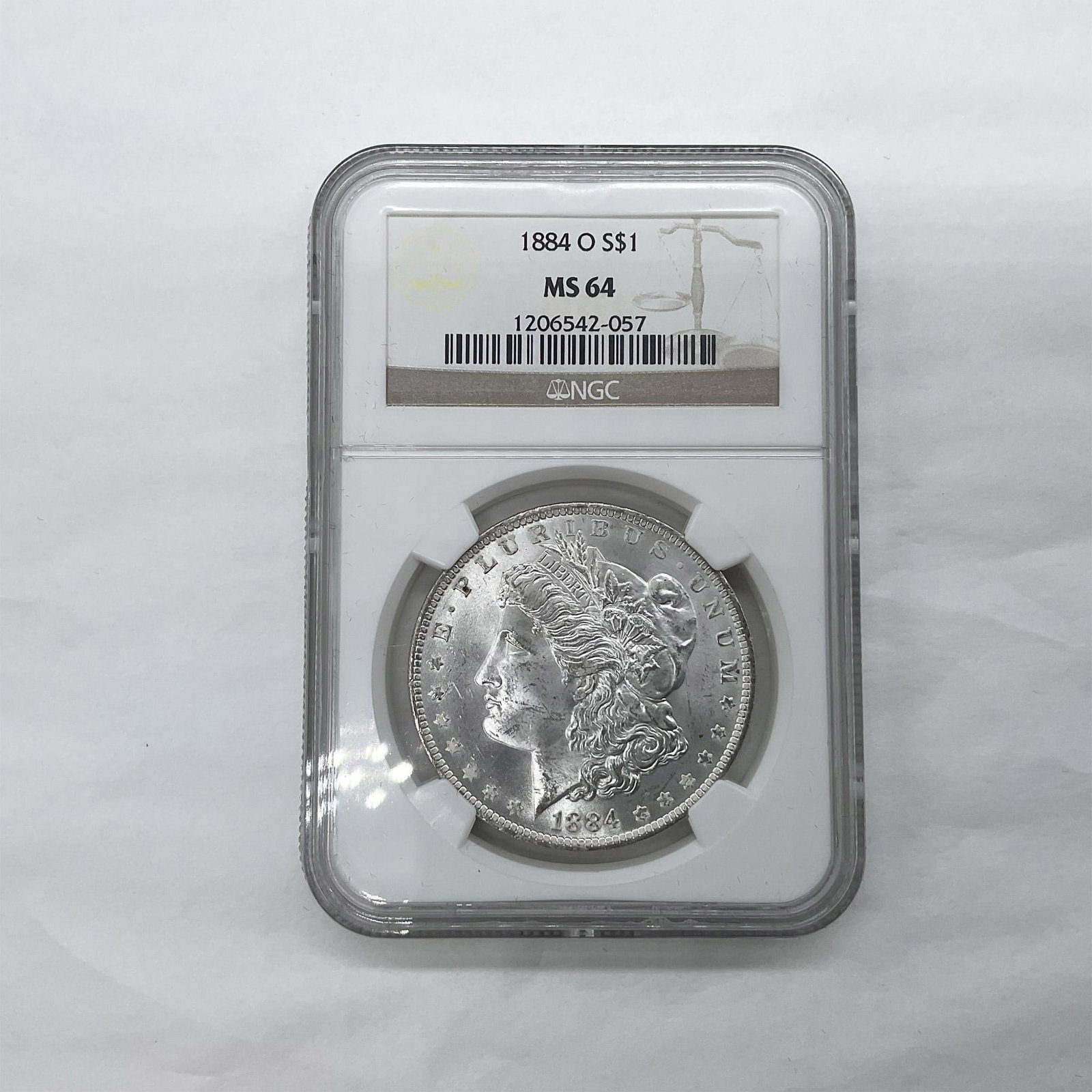 1884-O Morgan Silver Dollar NGC Graded MS64: New Orleans Mint. The obverse side features Liberty in profile. She is shown in cap, flora, and crown. The reverse side depicts an eagle with outstretched wings gripping arrows and an olive branch. Th