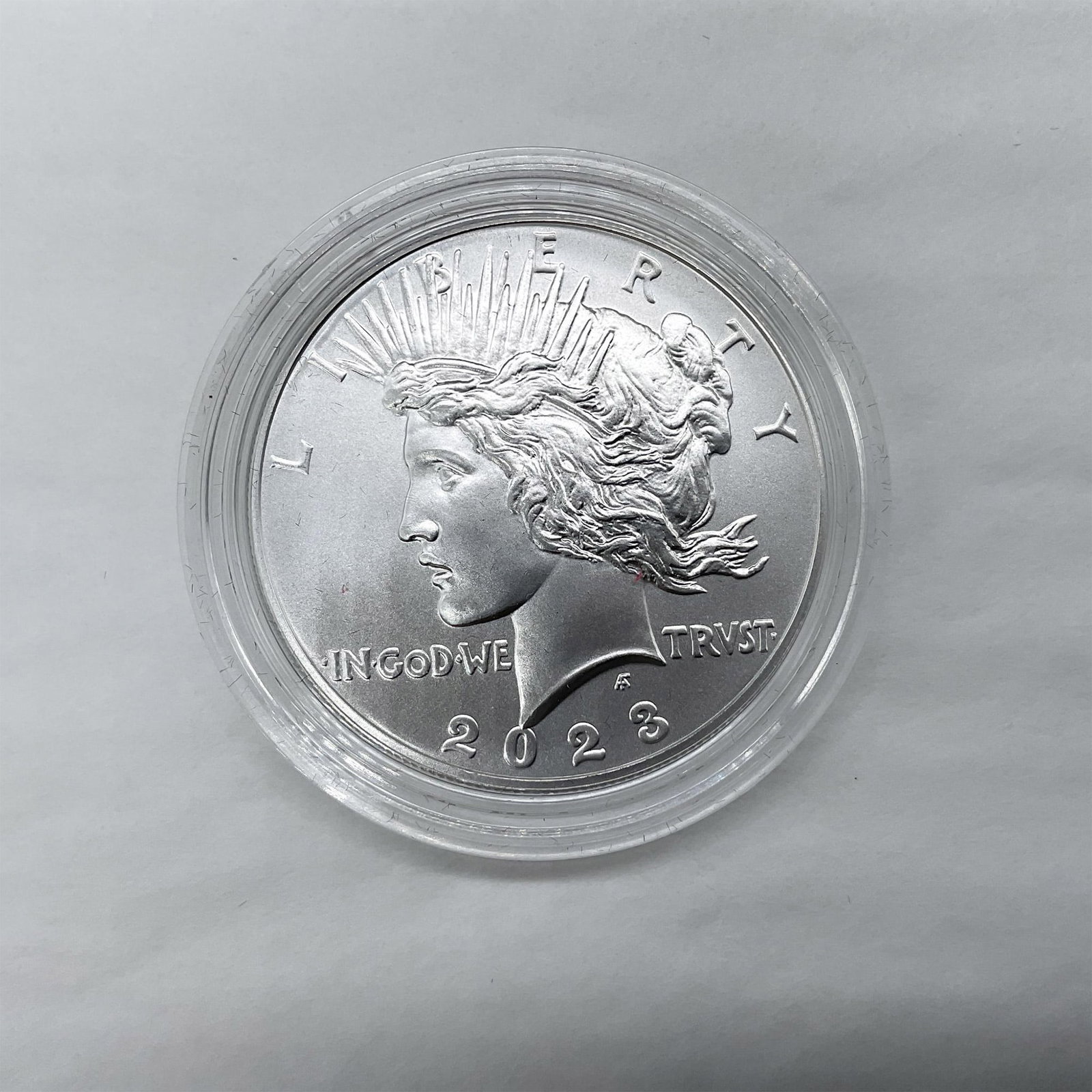 2023 (P) US Mint Peace Dollar Uncirculated Anniversary Coin: Philadelphia Mint. The obverse side features the profile of Liberty in a radiant crown, and the reverse side depicts an eagle perched on a rock, clutching olive branches. The coin is in a clear protec