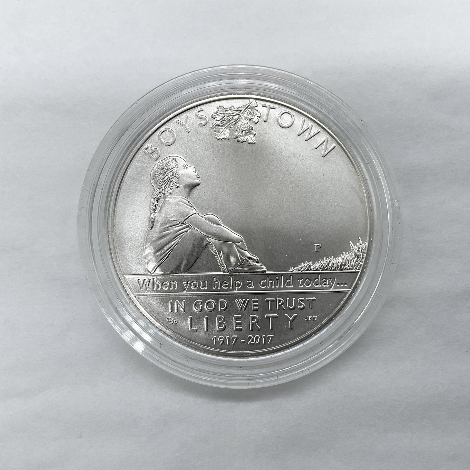 2017-P Boys Town Centennial Silver Dollar Uncirculated: Philadelphia Mint. A commemorative issued coin. The obverse side depicts a young girl sitting alone. She is shown gazing up into the branches looking for help. The reverse side depicts a family, inclu