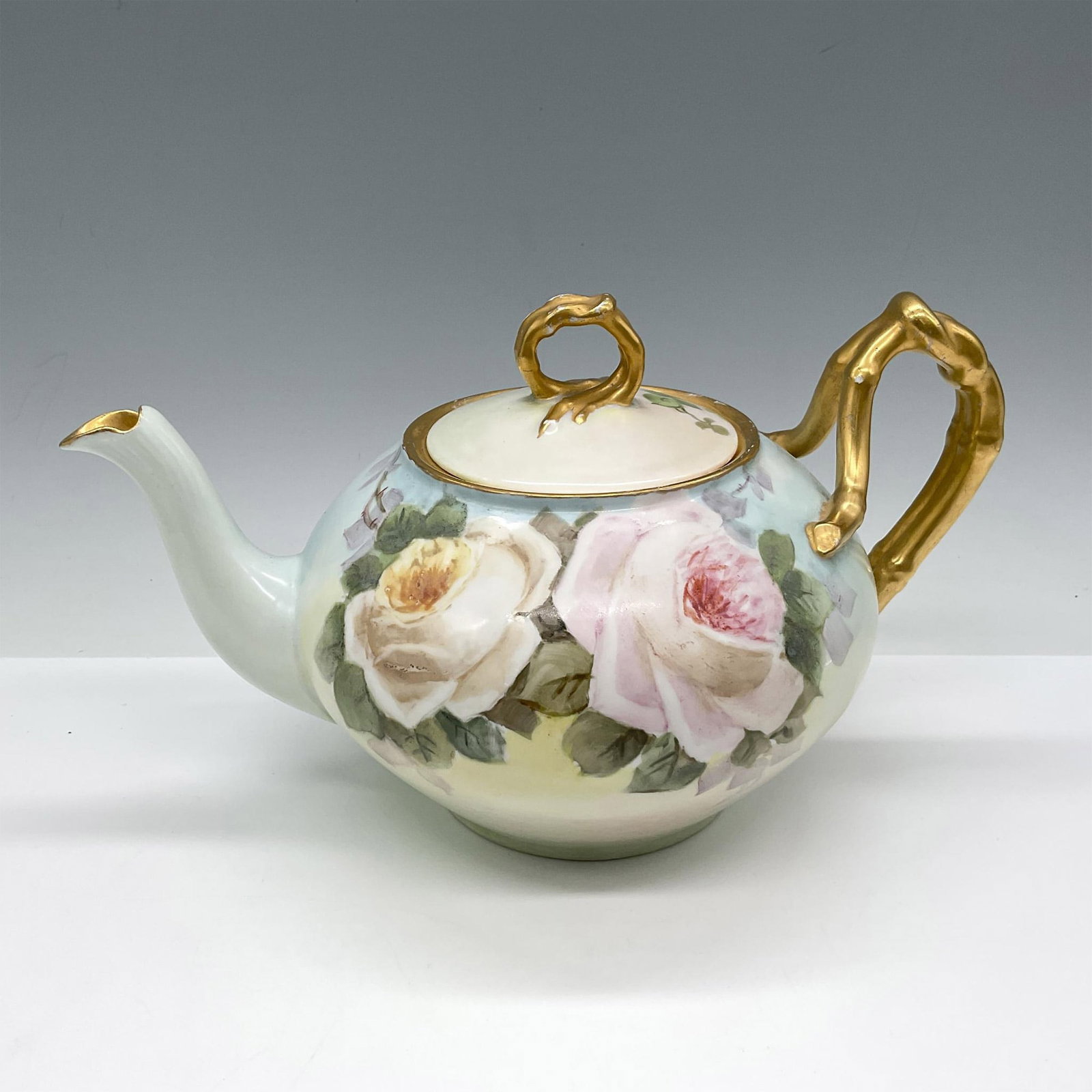 Jean Pouyat Limoges Porcelain Tea Pot: Lovely hand painted pastel coloration with large pink and yellow roses surrounded by green leaves. Gilt accents added to handle, spout, rim and lid handle. J.P. L France backstamp. Issued: 20th centur