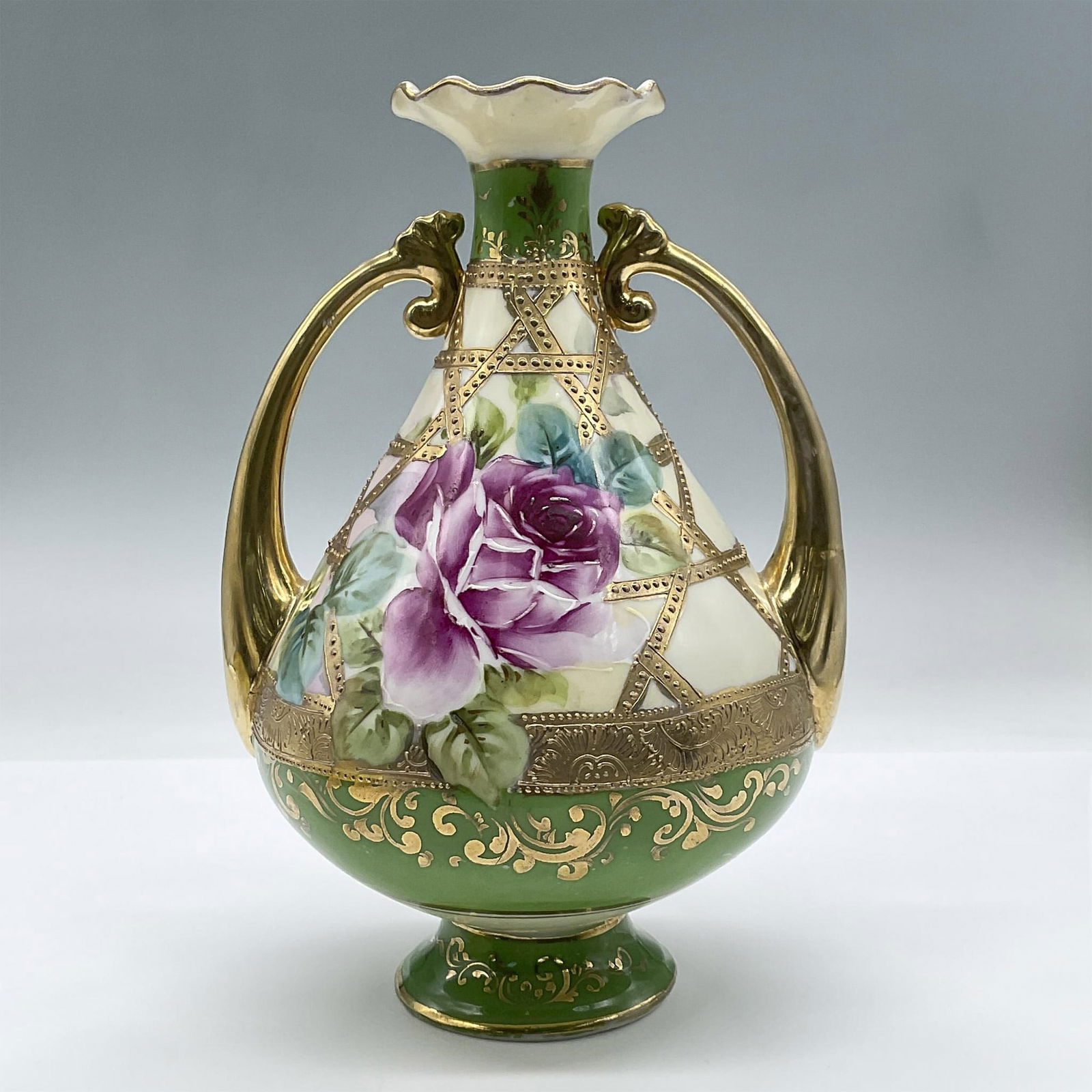 Vintage Nippon Porcelain Vase with Handles: This exquisite hand painted vase features a large purple floral design and gilded gold handles and details. Nippon Backstamp. Issued: 20th century Dimensions: 6"L x 5"W x 8.25"H Manufacturer: Nippon C