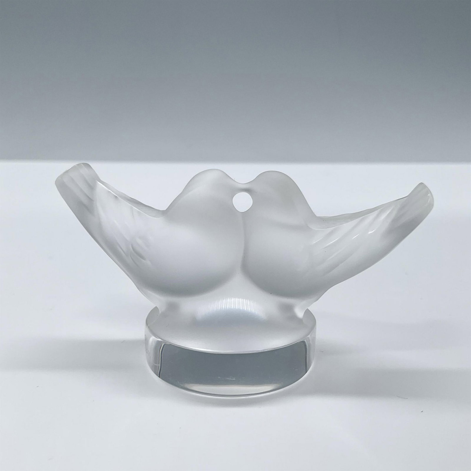 Lalique Frosted Crystal Figurine, Two Doves: Two frosted doves kissing on a clear base. Can be used as a place card holder. Lalique France etched on the side of the base. Dimensions: 1.5"L x 3"W x 1.75"H Manufacturer: Lalique Country of Origin: 