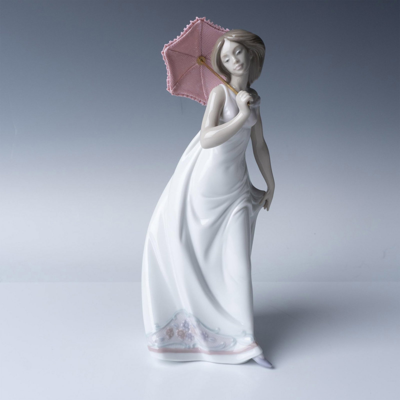 Lladro Porcelain Figurine Afternoon Promenade 7636: This is a Lladro porcelain figurine, model number 07636, titled Afternoon Promenade. The elegant figure depicts a woman in a flowing dress holding an umbrella over her shoulder, evoking the tranquilit
