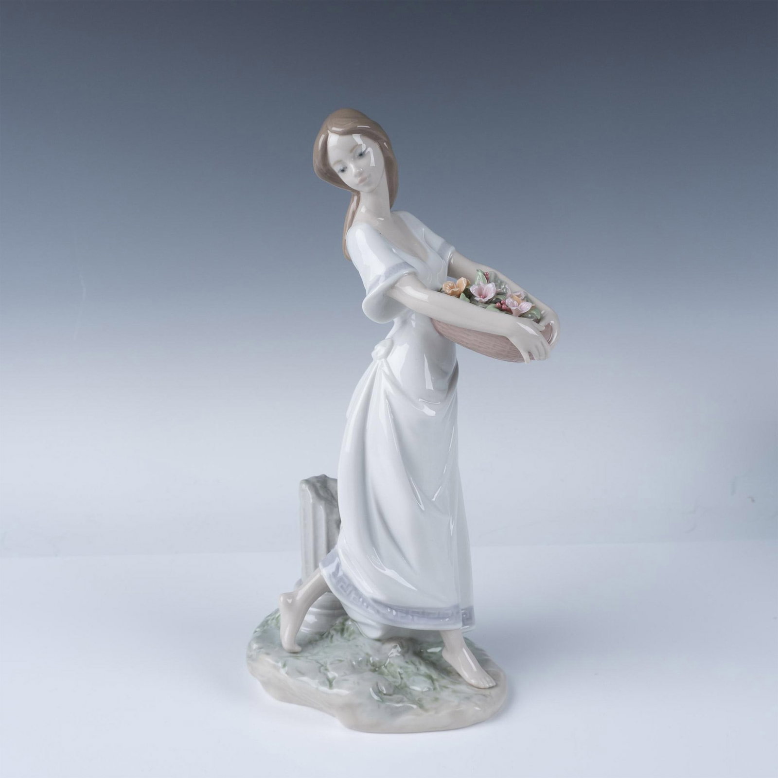 Lladro Porcelain Figurine Gardens of Athens 7704: Lladro Gardens of Athens figurine, model number 07704, beautifully portrays a serene woman gracefully carrying a basket brimming with hand-sculpted pastel flowers. Designed by Jose Luis Santes and int