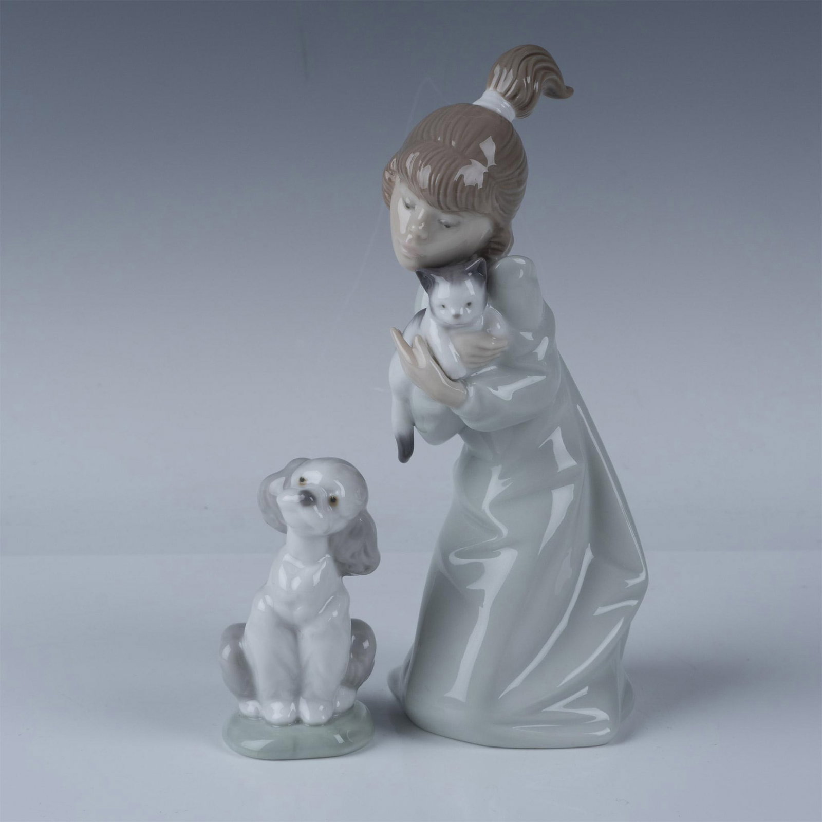 2pc Lladro Figurines Sleepy Kitten and A Friend For Life: This auction lot features two charming Lladro porcelain figurines Sleepy Kitten, model number 1005712, depicts a young girl gently cradling a sleepy kitten, issued in 1990 and retired in 2002, measuri