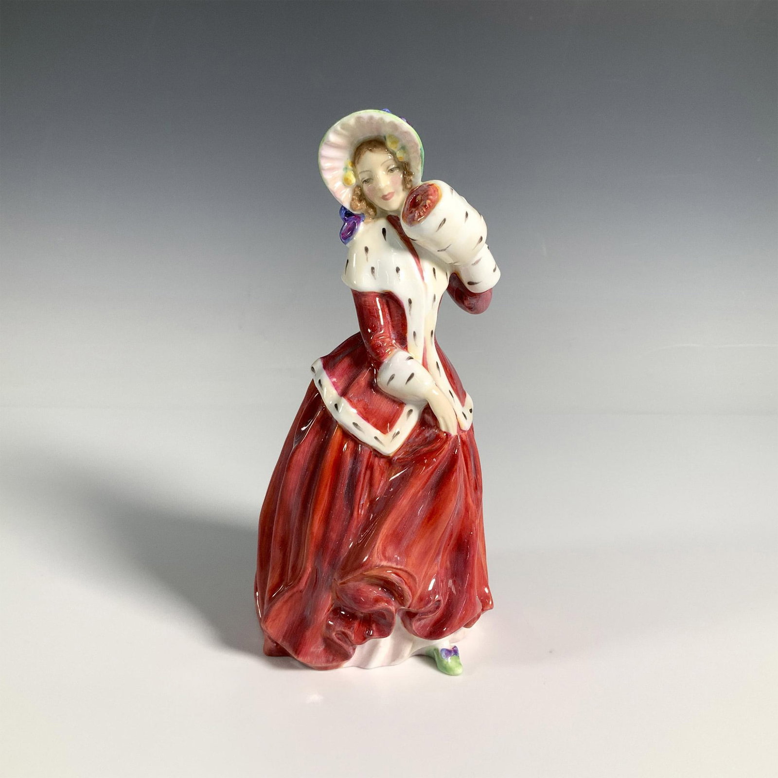 Christmas Morn HN1992 - Royal Doulton Figurine: Glossy figure of a woman dressed in elegant winter attire and bonnet. Red and white coloration. Royal Doulton backstamp. Artist: Peggy Davies Issued: 1947 - 1996 Dimensions: 3.5"L x 3.5"W x 7.25"H Man