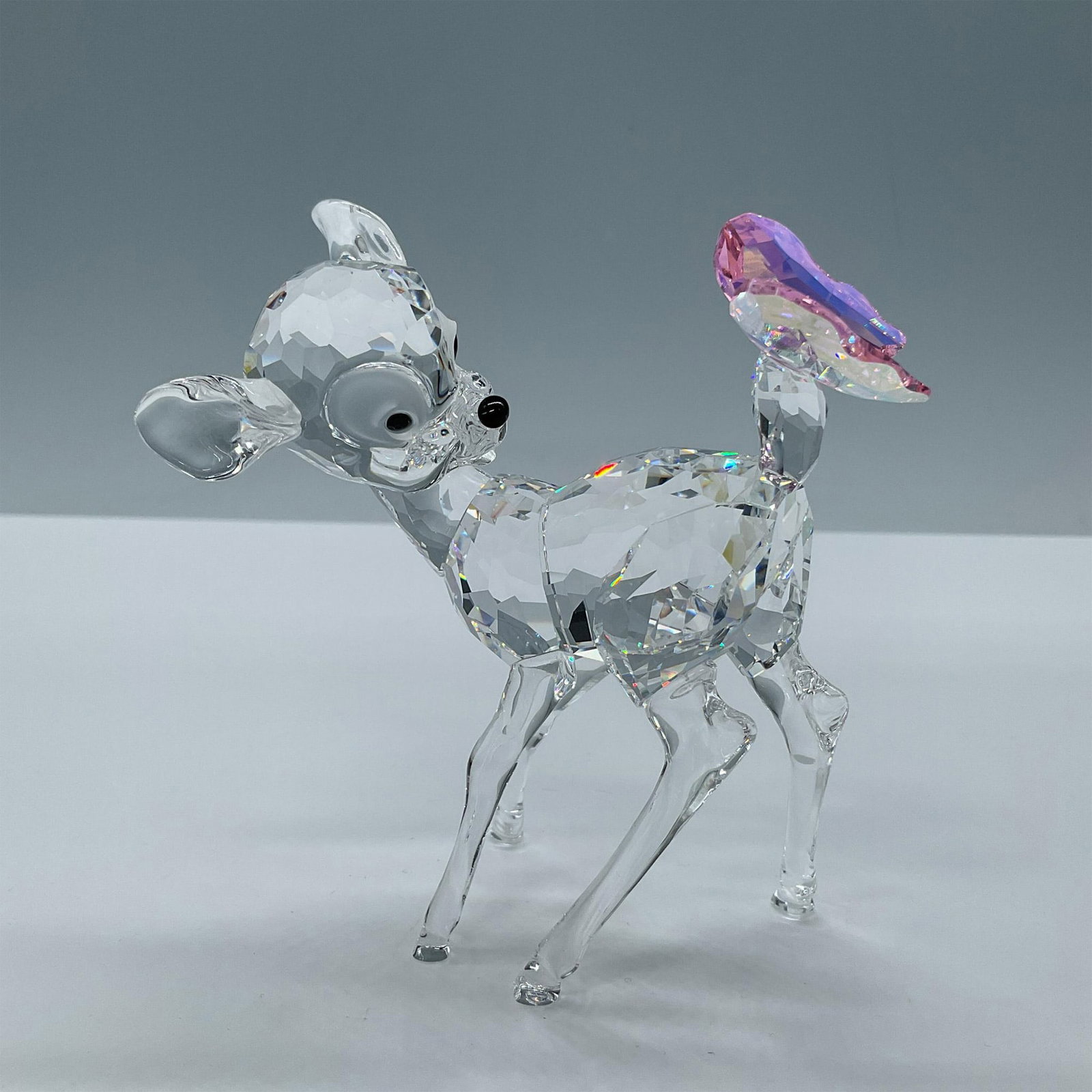 Swarovski Crystal Figurine, Disney Bambi: Beautiful clear crystal. Features a facetted body and frosted eyes with jet black pupils. Completed by an adorable rosaline crystal butterfly in its tail. Swarovski etched backstamp. Includes the orig