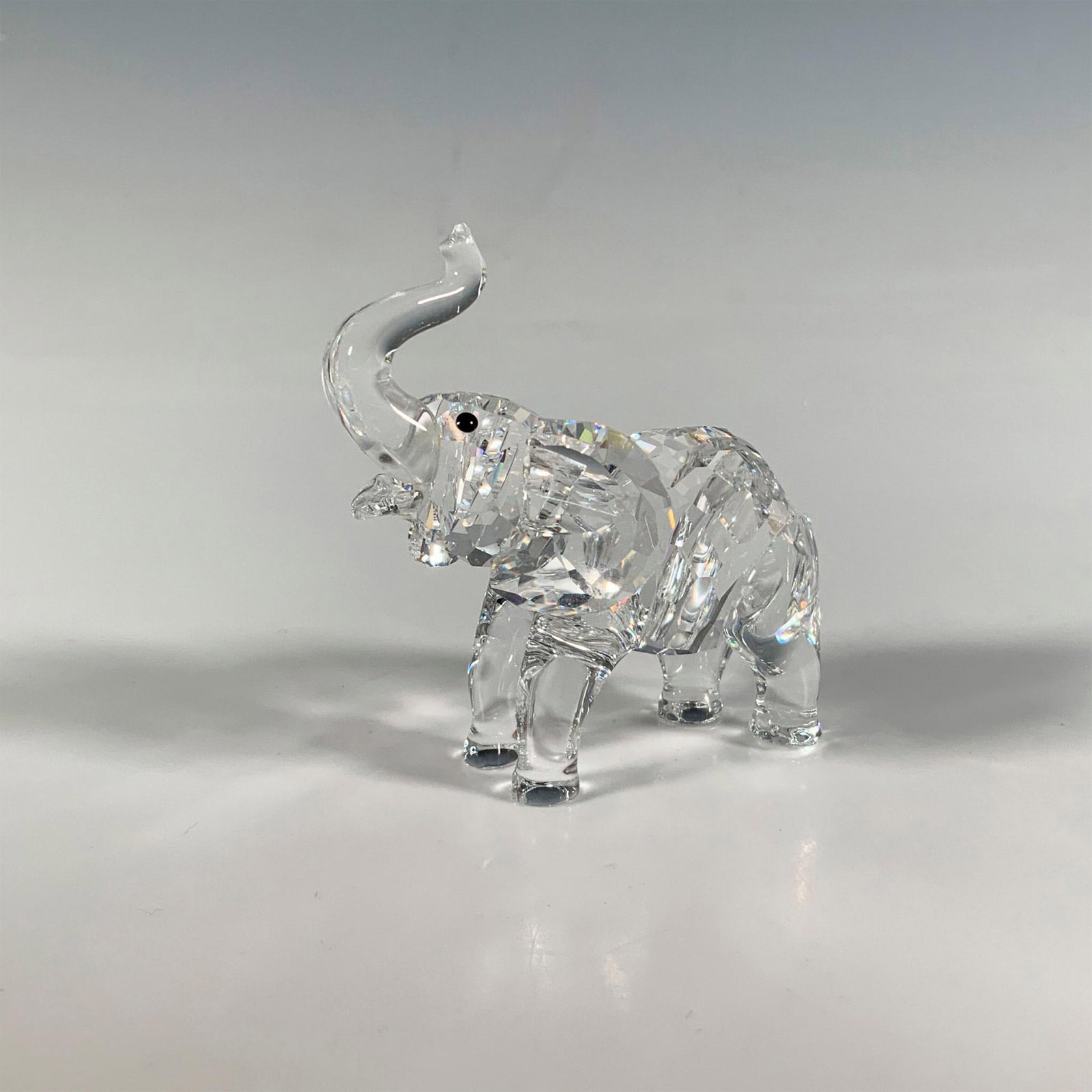 Swarovski Crystal Figurine, Baby Elephant: A sweet clear faceted figure of a young elephant with smooth black eyes. Swarovski marking. Artist: Martin Zendron Issued: 1995-2012 Dimensions: 2.5"L x 1.5"W x 2.5"H Manufacturer: Swarovski Country o