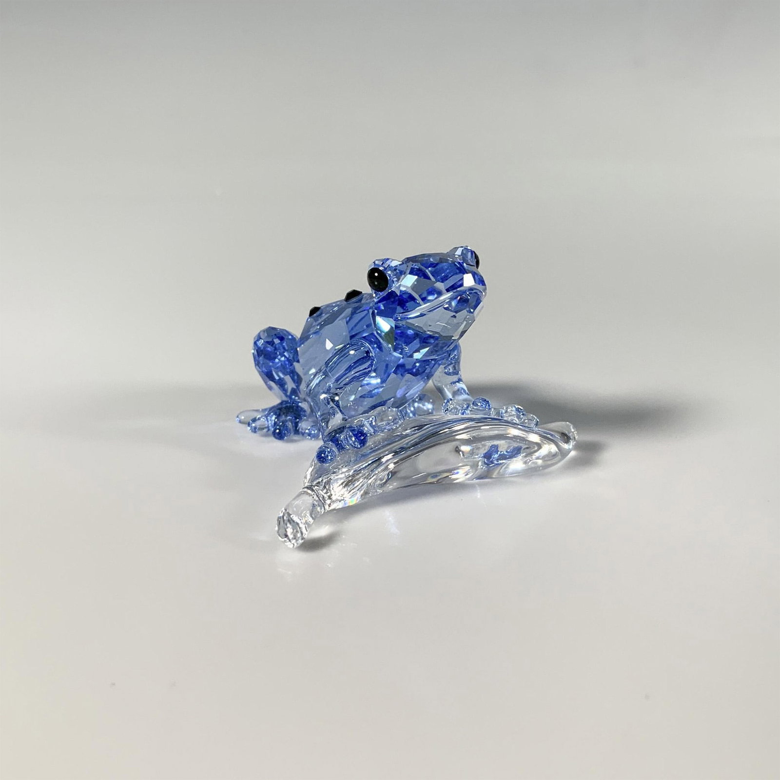 Swarovski Crystal SCS 2009 Figurine, Dart Frog: A small facet-cut blue crystal figure of a frog perched on a leaf, adorned with black gemstones. A limited edition item available only to SCS members in 2009. Swarovski marking. This item has its orig