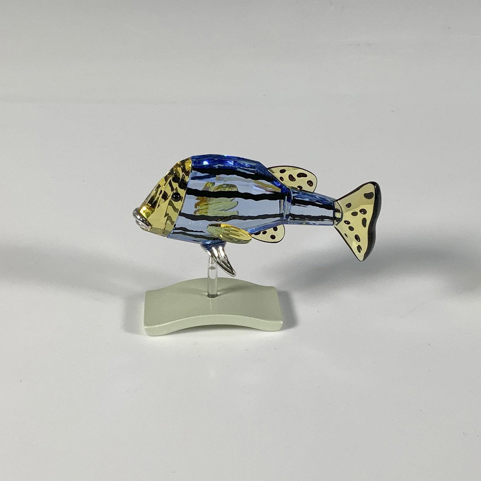 Swarovski Crystal Fish Figurine, Cantumbela Light Sapphire: A brilliant aquatic creature, part of the Exotic Fish and South Sea collection, crafted from blue and yellow crystal, embellished with black stripes and spots. Swarovski marking. This item has a base 