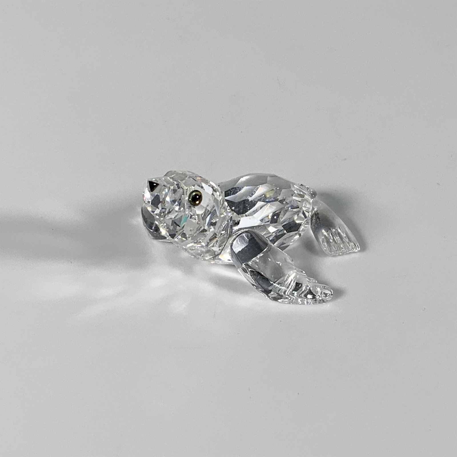 Swarovski Crystal Figurine, Baby Sea Lion: Part of the Aquatic Worlds group, this charming clear faceted figure of a sea lion pup features iridescent eyes and a black nose. Swarovski mark. This item has its original box: 3.25"W x 4.75"H. Artis