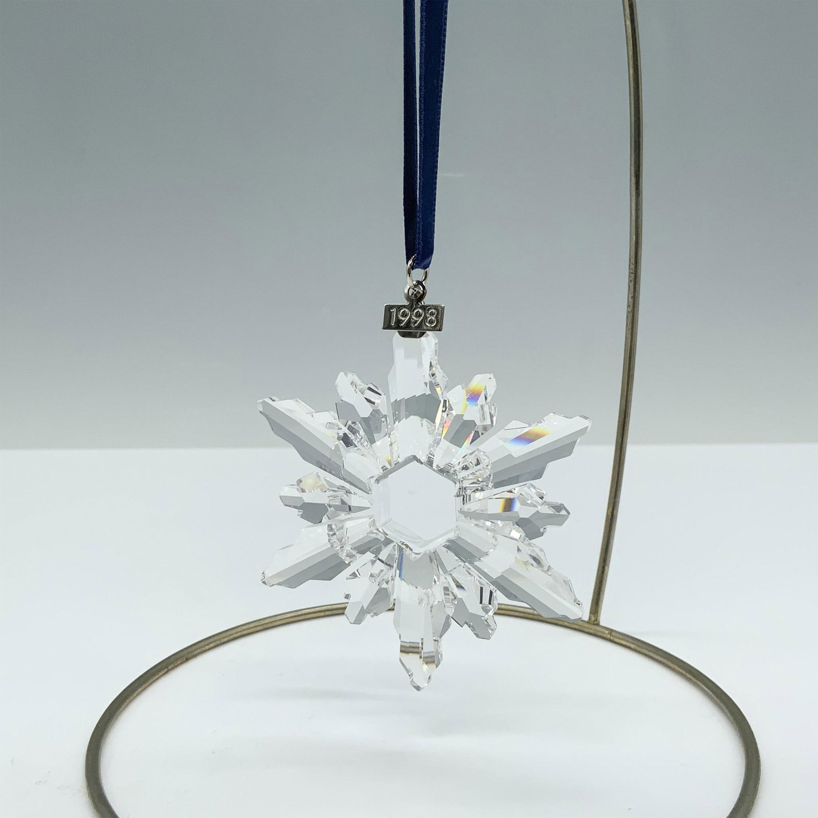 Swarovski Crystal Ornament, 1998 Christmas Ornament: Limited edition crystal ornament with a metal tag reading 1998 as well as 6 short points and 6 long points that depict a beautiful snowflake design. Swarovski backstamp. 220037. This item has its orig
