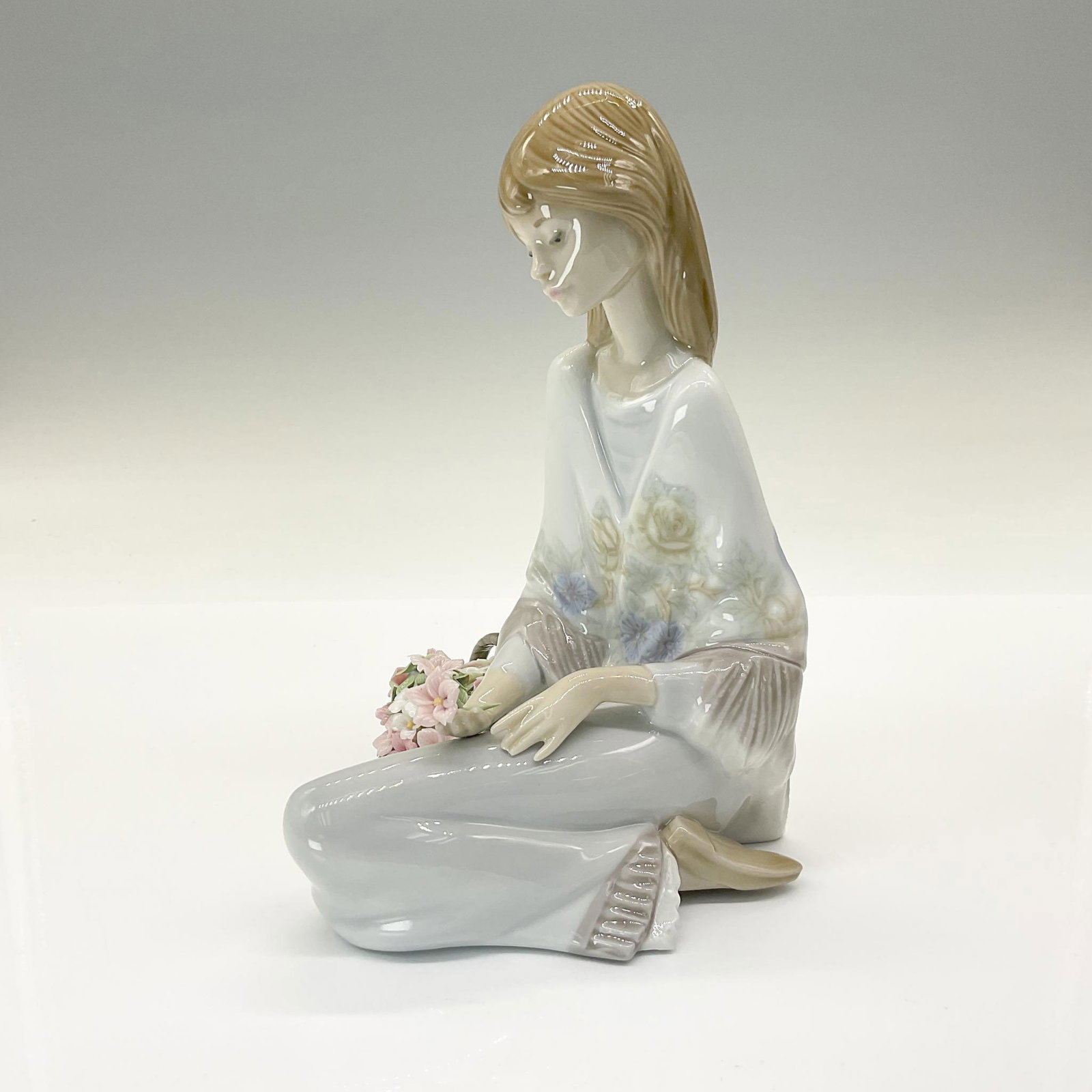Flower Song 01007607 - Lladro Porcelain Figurine: Glossy porcelain figurine, depicting a woman with a basket of flowers. Lladro backstamp. This item has its original box: 7.5"L x 13"W x 6"H. Artist: Juan Huerta Issued: 1988 Dimensions: 5.25''L x 4.25